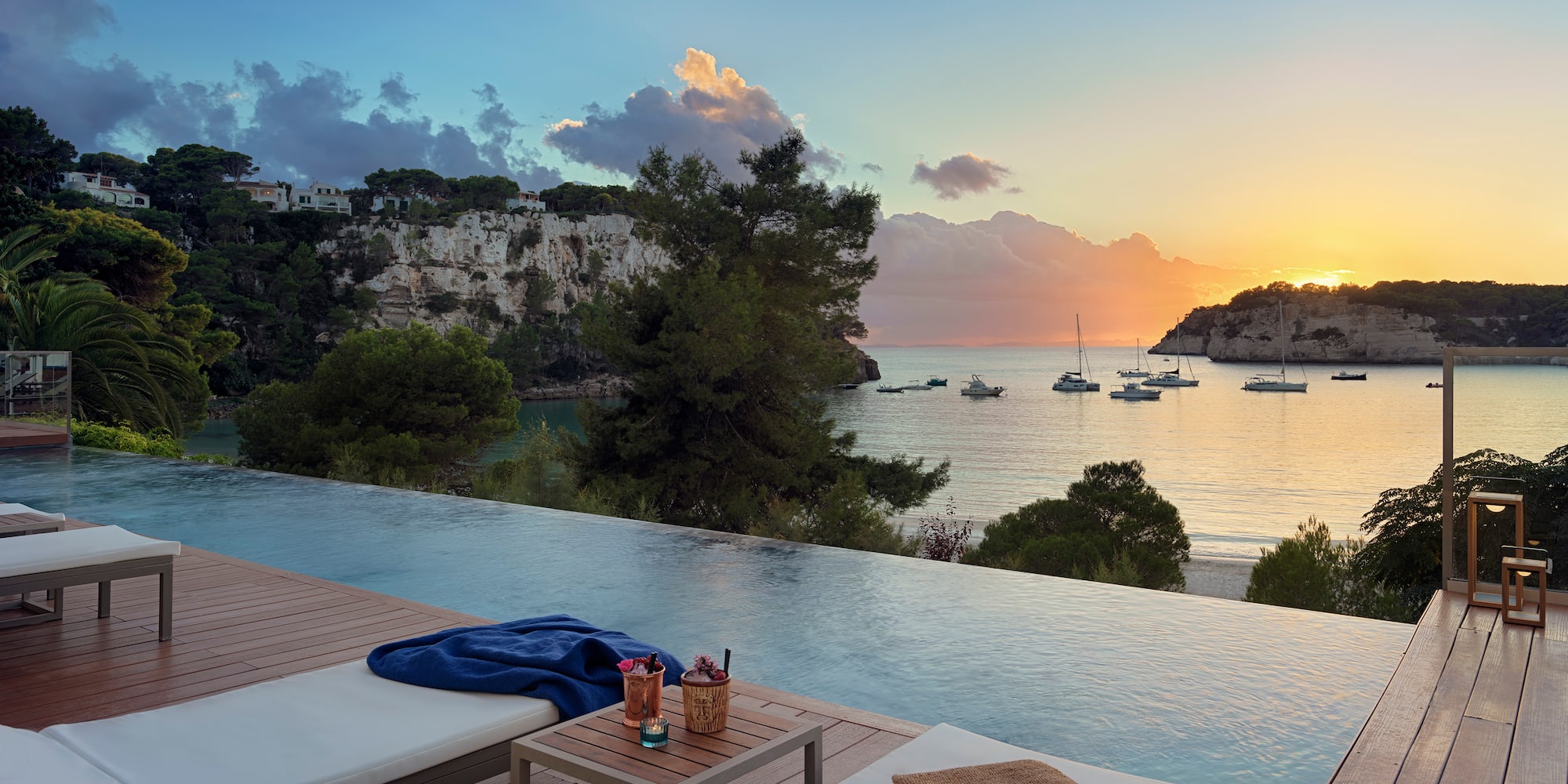 a pool with a view of the ocean and boats in the background