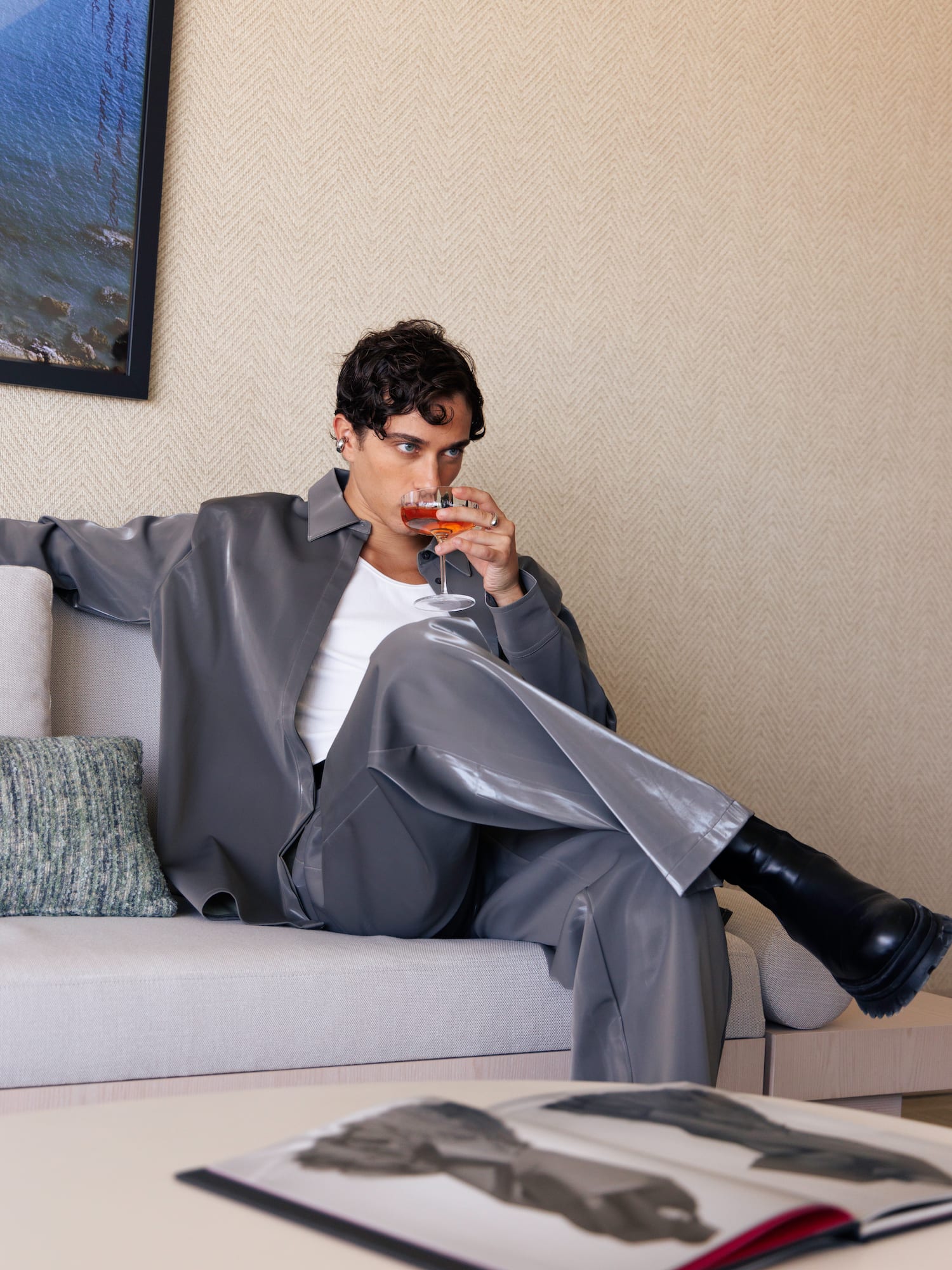 a man sitting on a couch drinking from a glass