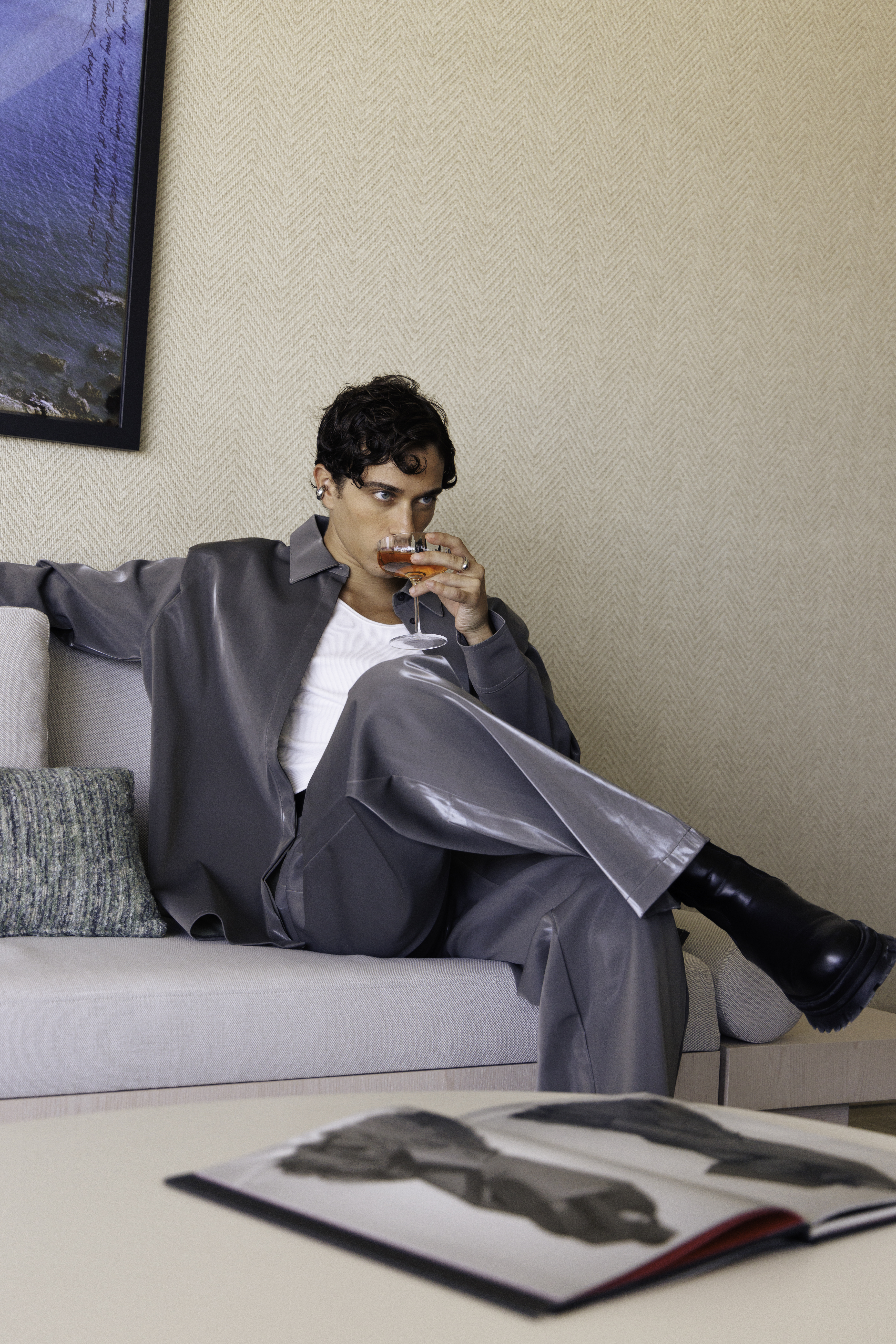 a man sitting on a couch drinking from a glass