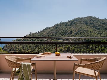 a table and chairs on a balcony overlooking a mountain