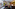 Elegant hotel lobby with black marble floor, gold reception desk, and pink lounge sofa.