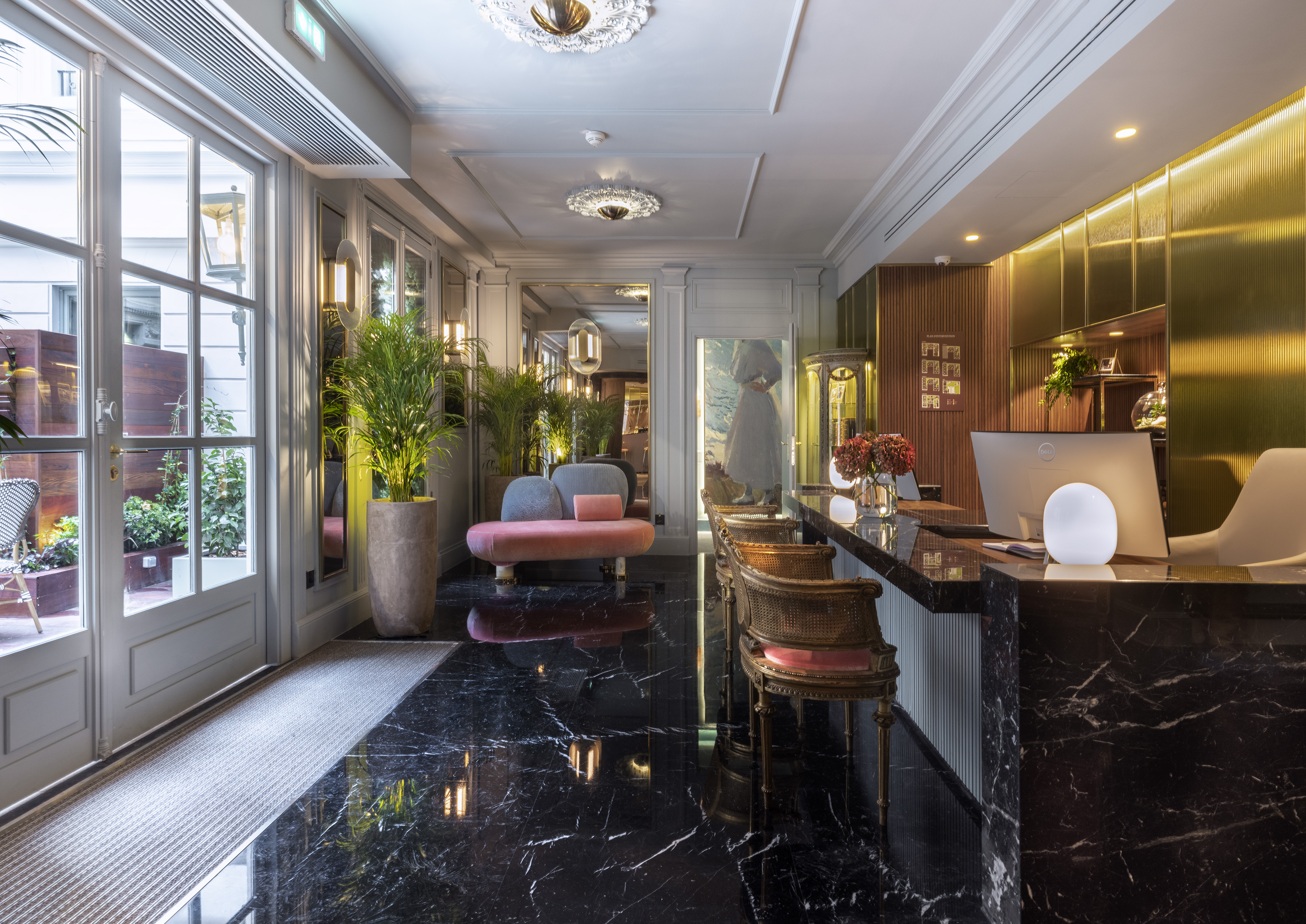Elegant hotel lobby with black marble floor, gold reception desk, and pink lounge sofa.