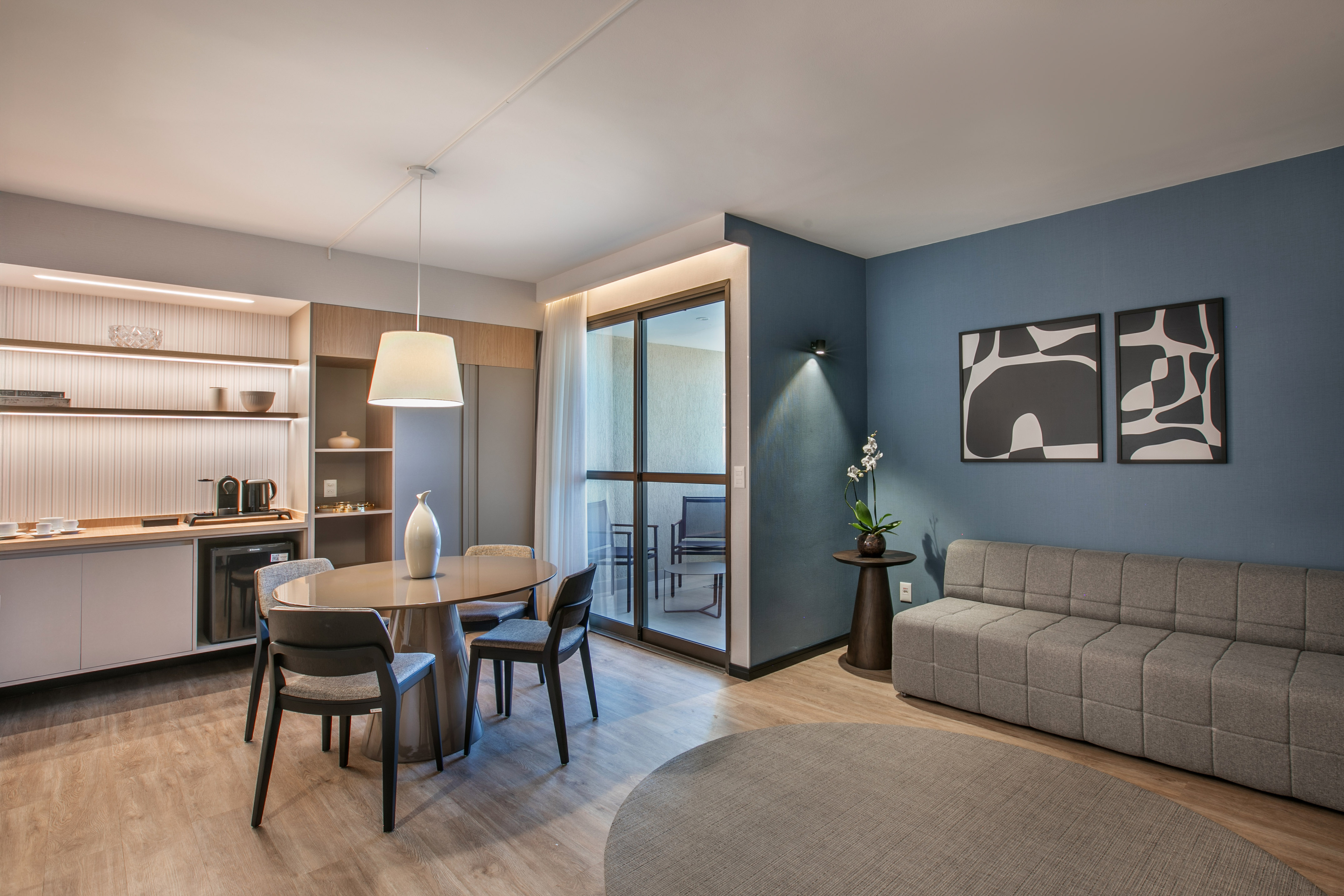 Contemporary apartment living: dining, kitchenette, grey sofa, blue wall.