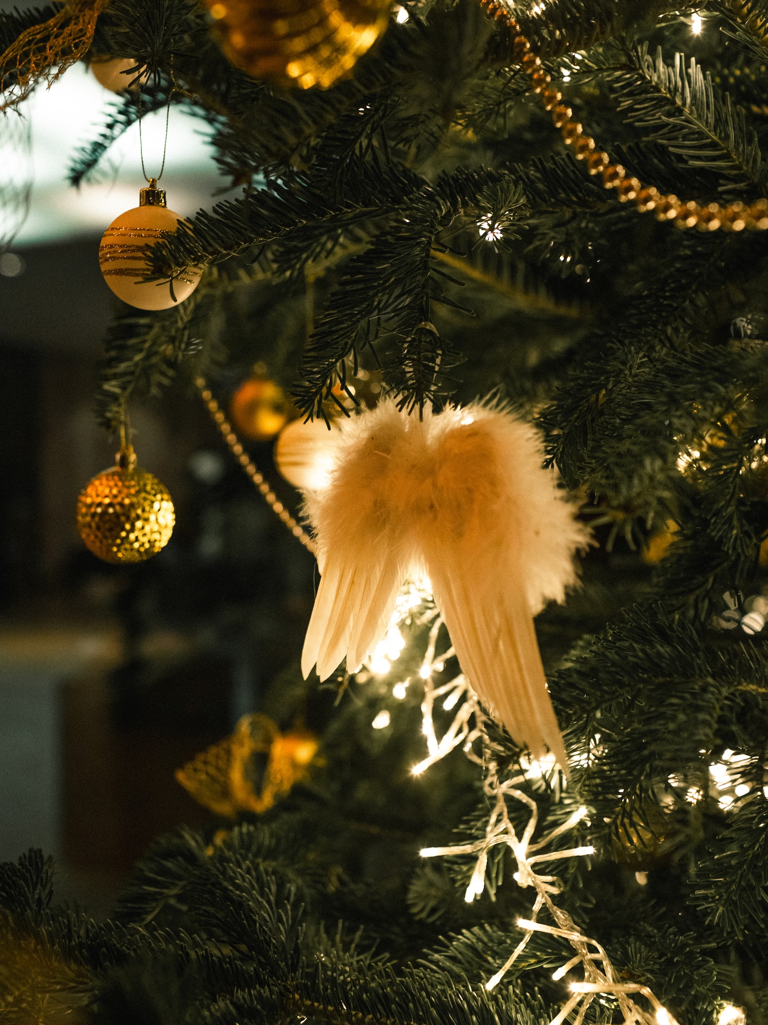 Festive Christmas tree with fluffy angel wings, gold baubles, and sparkling lights.