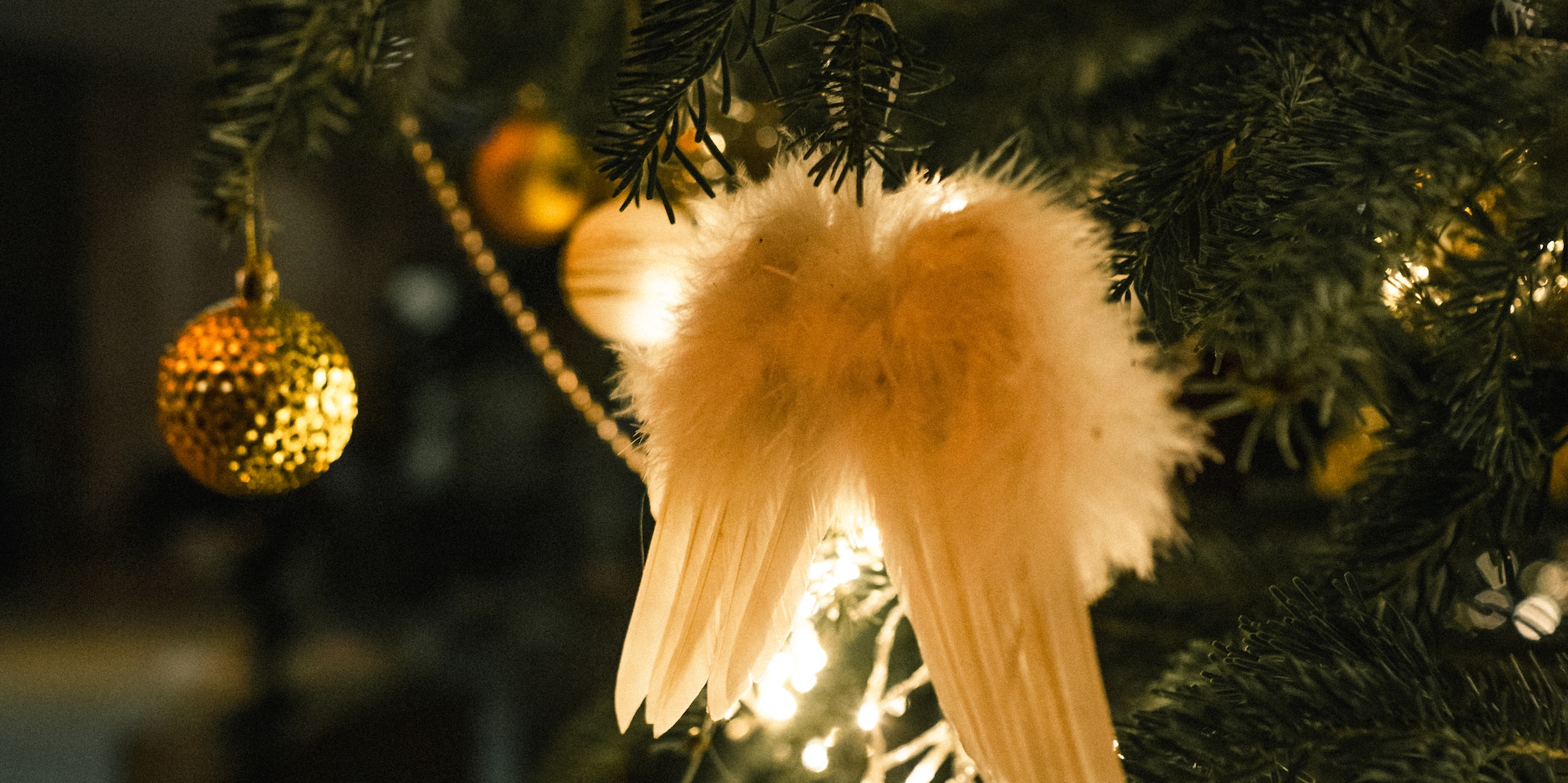 Festive Christmas tree with golden ornaments, soft lights, and angel wings.