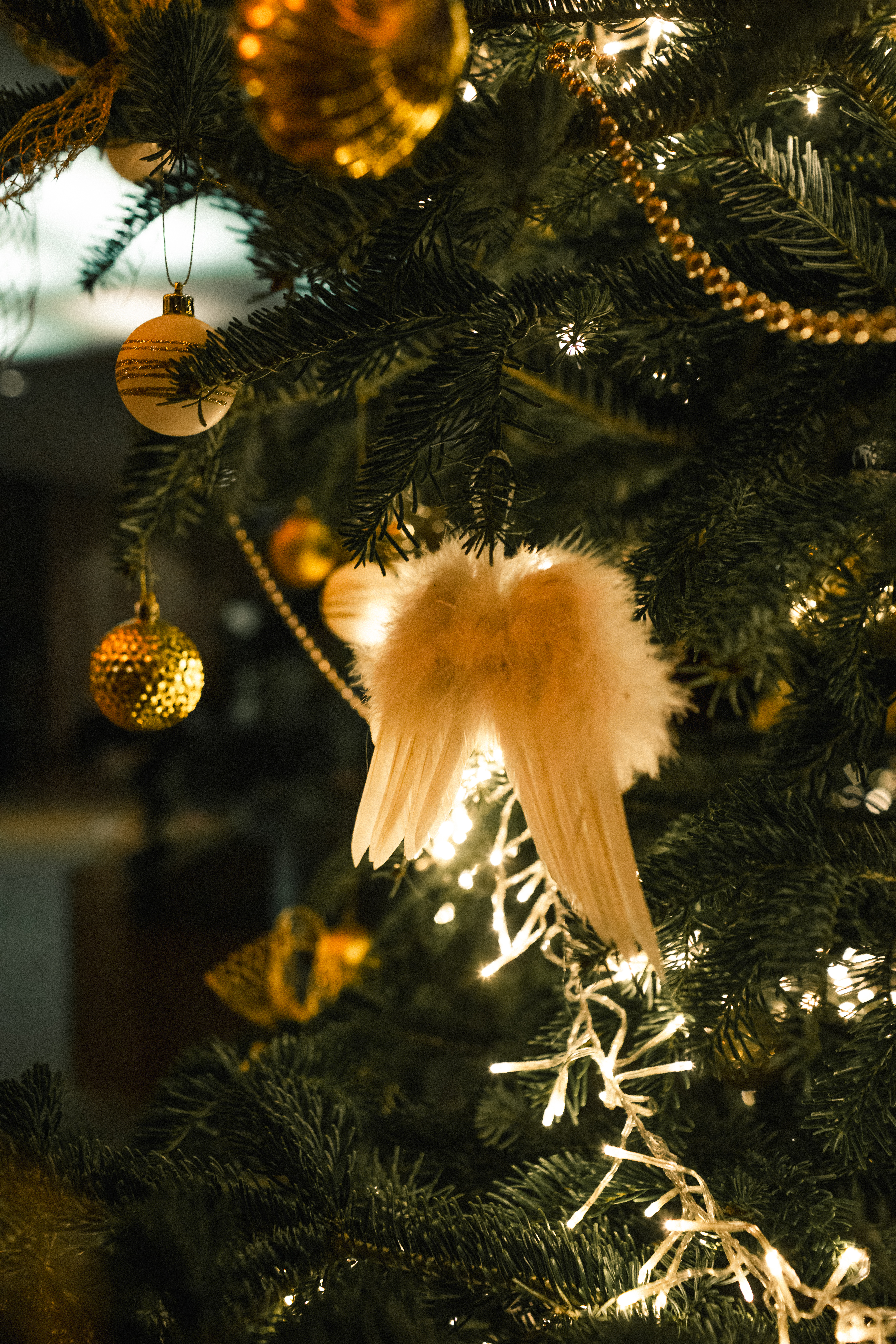 Festive Christmas tree with fluffy angel wings, gold baubles, and sparkling lights.