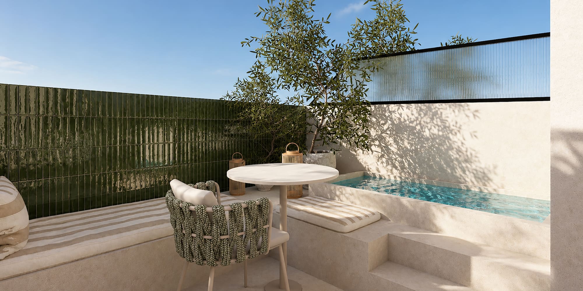 Patio mediterráneo con piscina, azulejos verdes, mesa redonda y olivo.