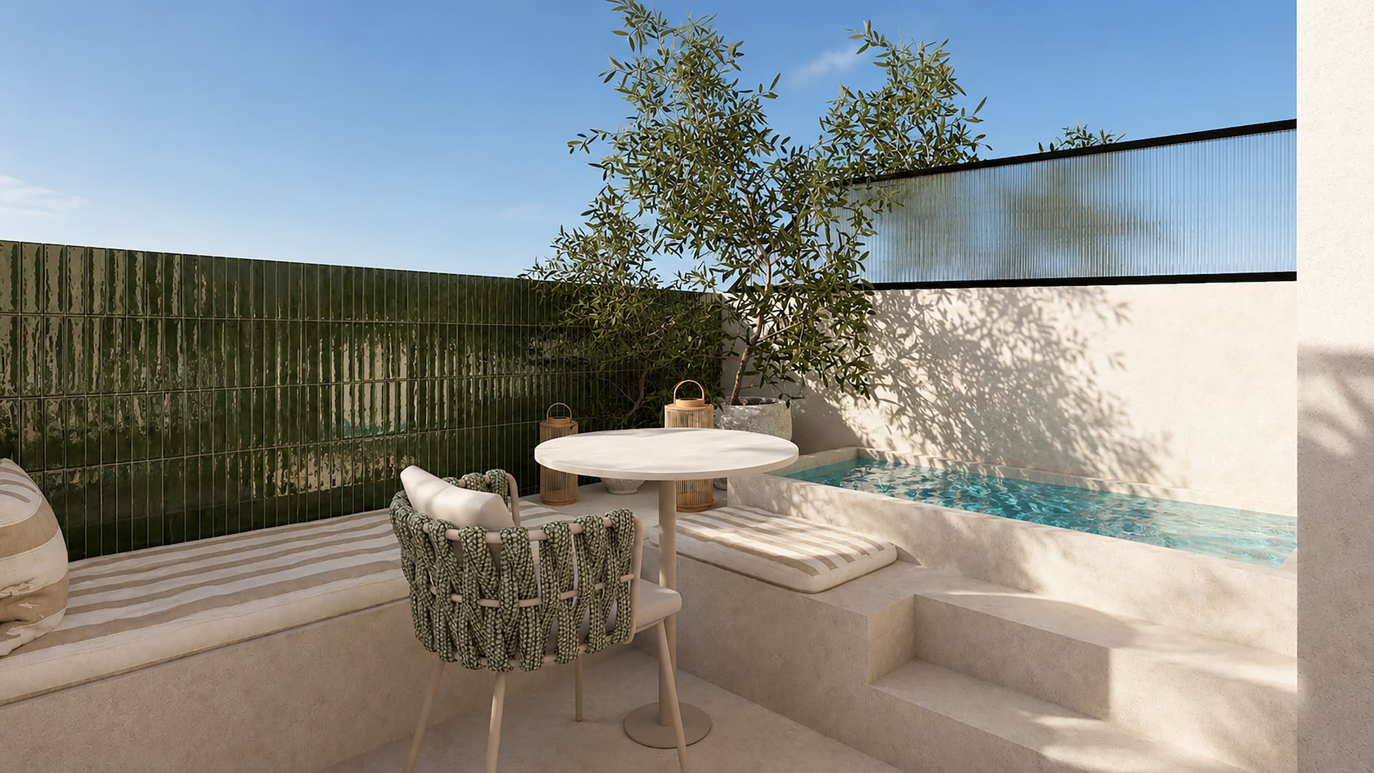 Patio mediterráneo con piscina, azulejos verdes, mesa redonda y olivo.
