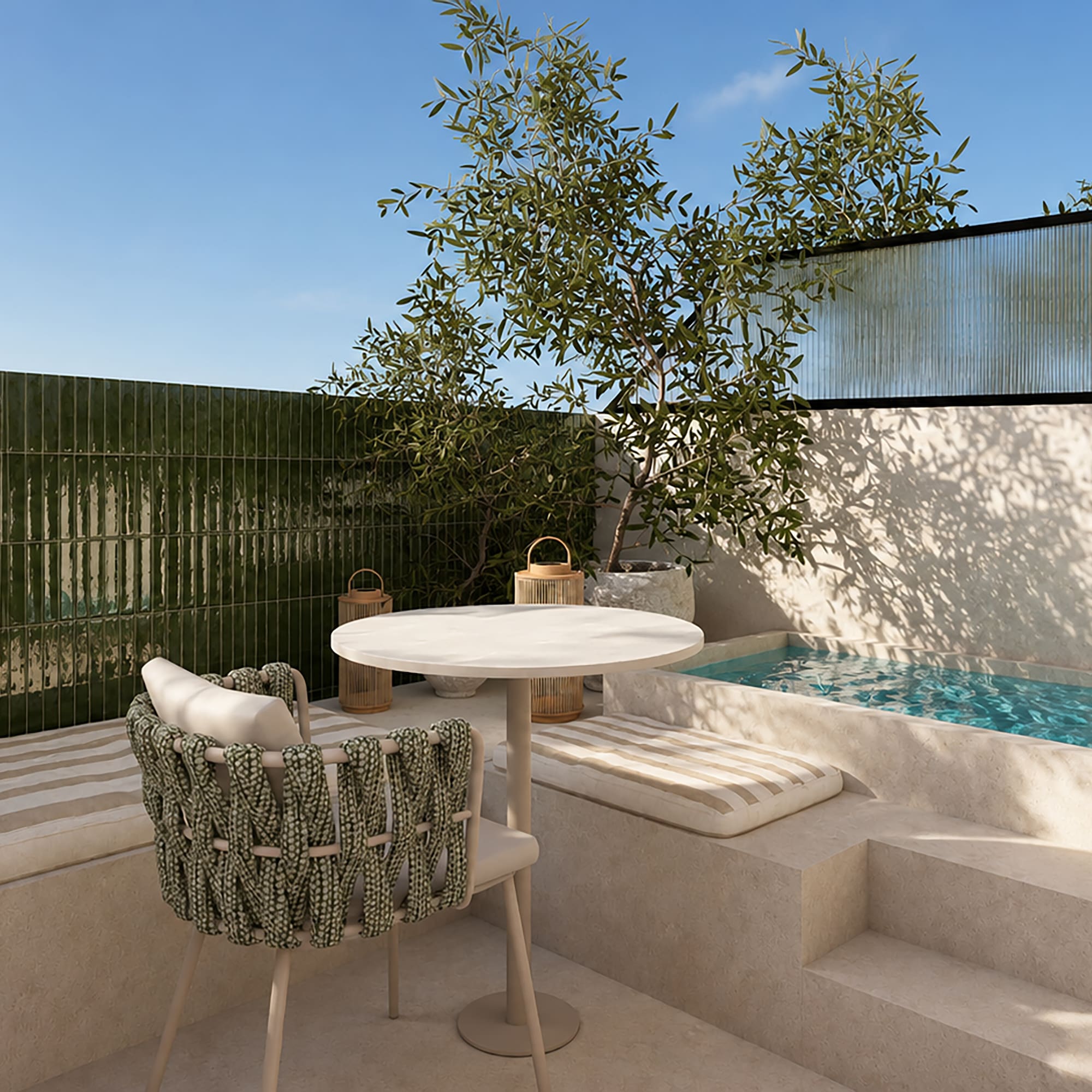 Patio mediterráneo con piscina, azulejos verdes, mesa redonda y olivo.
