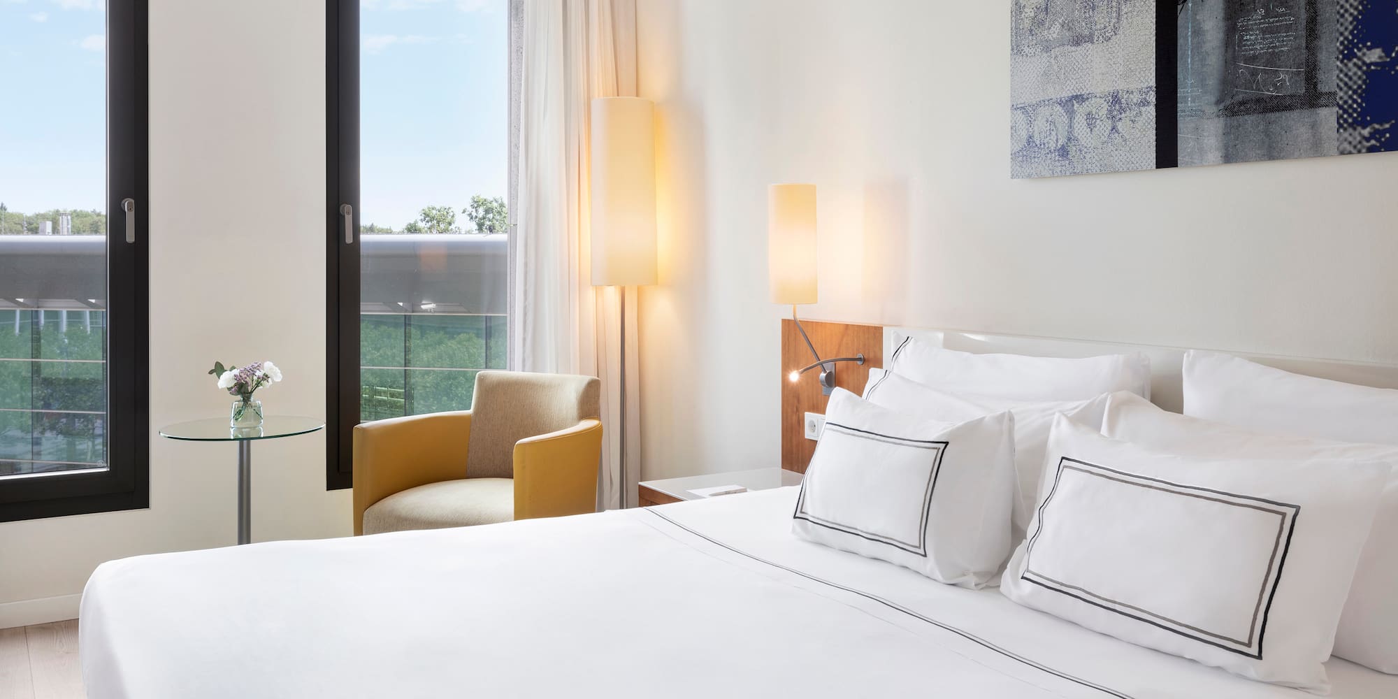 a bed with white sheets and pillows in a hotel room