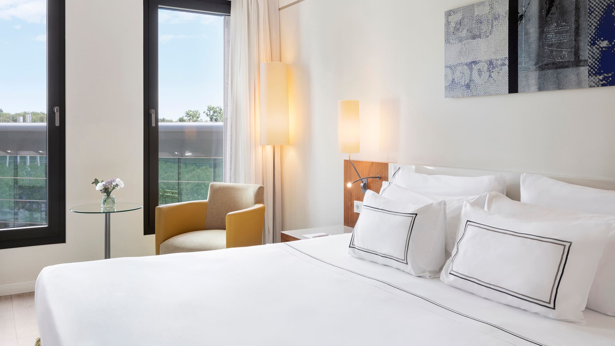 a bed with white sheets and pillows in a hotel room
