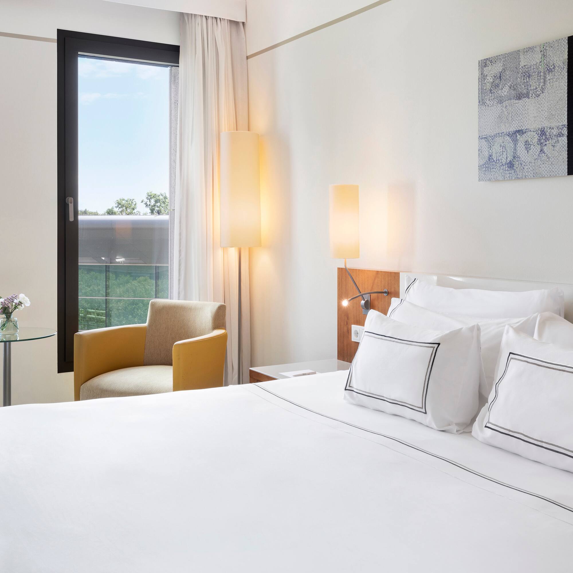 a bed with white sheets and pillows in a hotel room