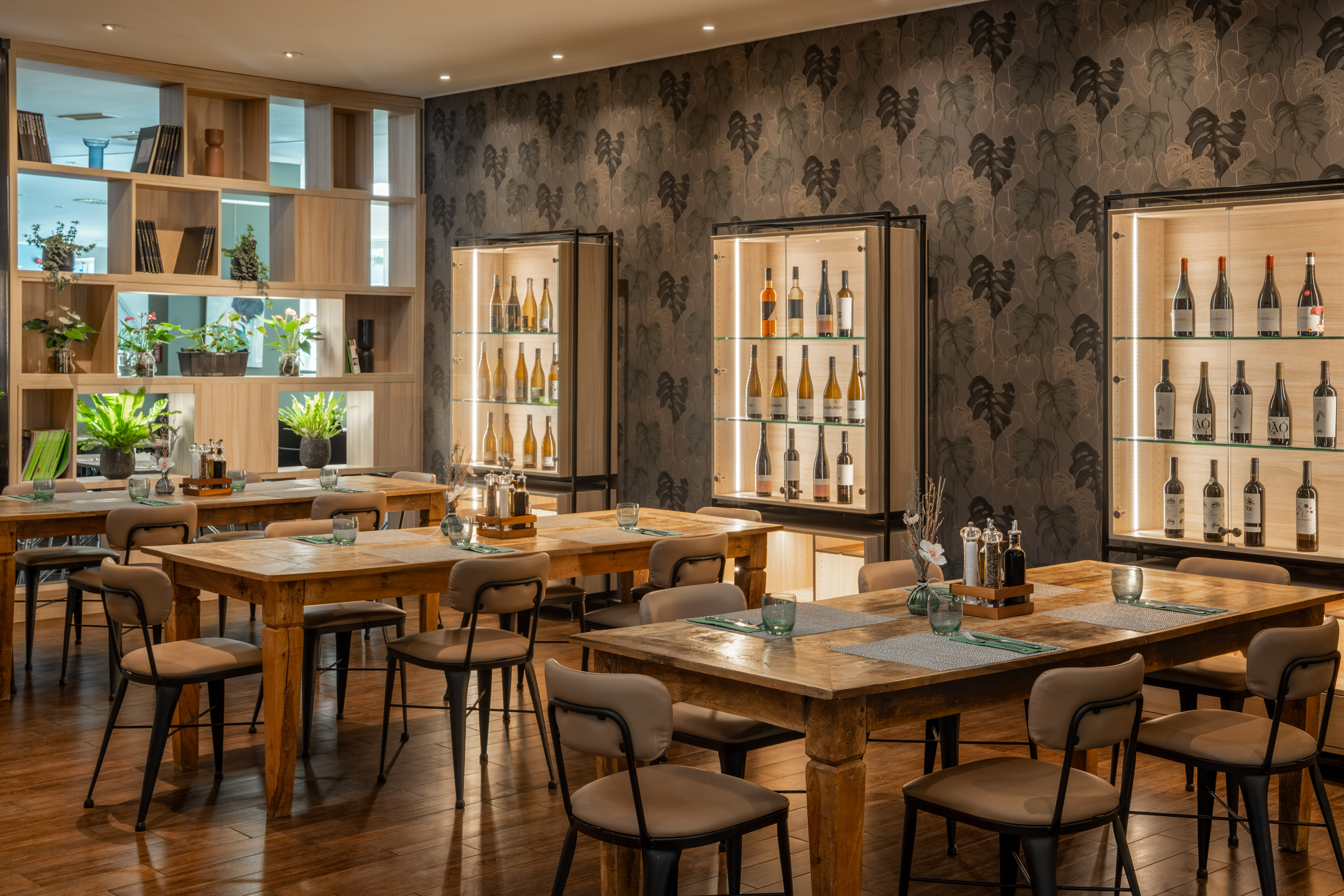 Restaurant dining area with wooden tables, wine displays, and modern decor.