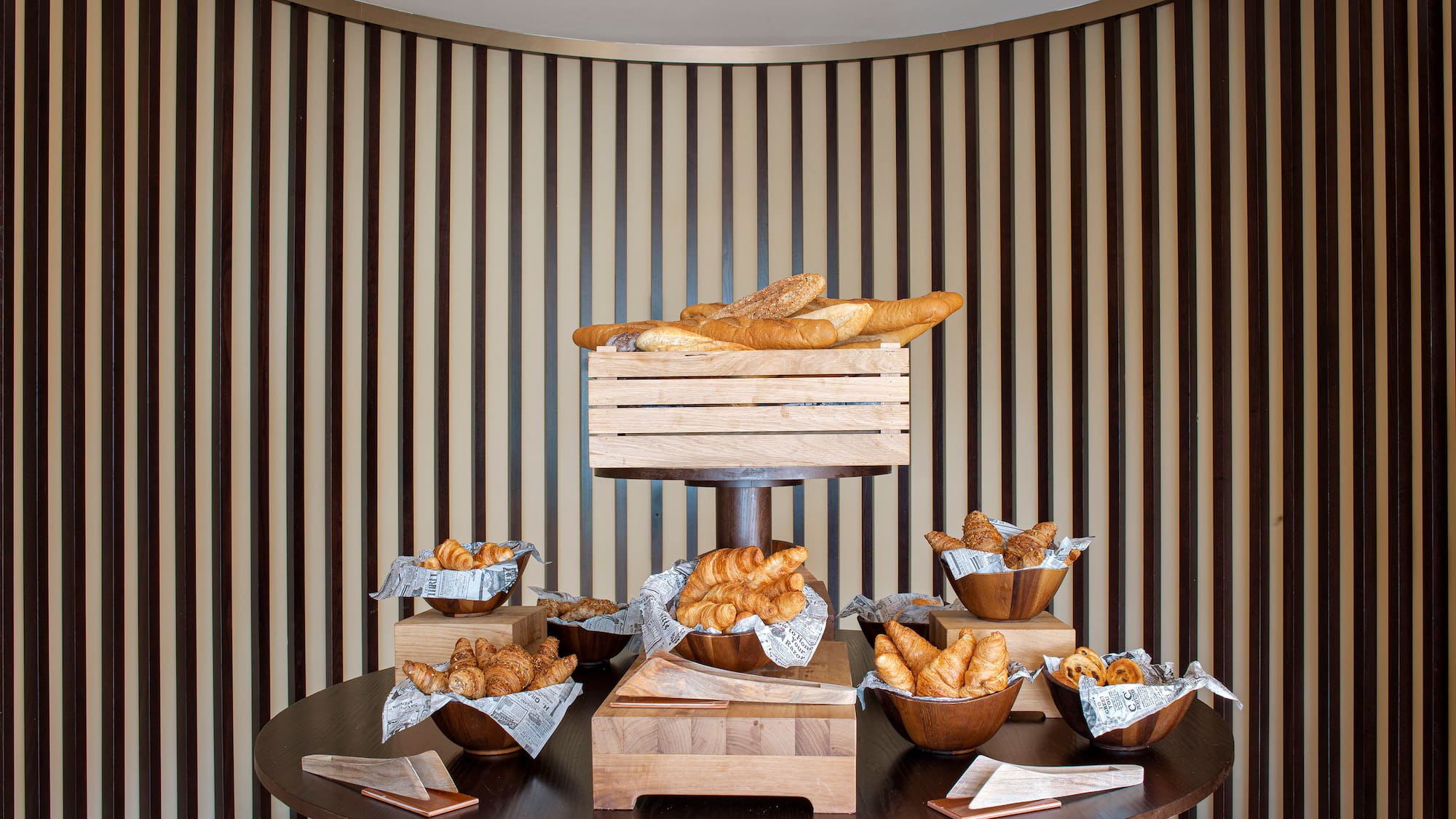 Fresh croissants, baguettes, and pastries on a hotel breakfast buffet display.