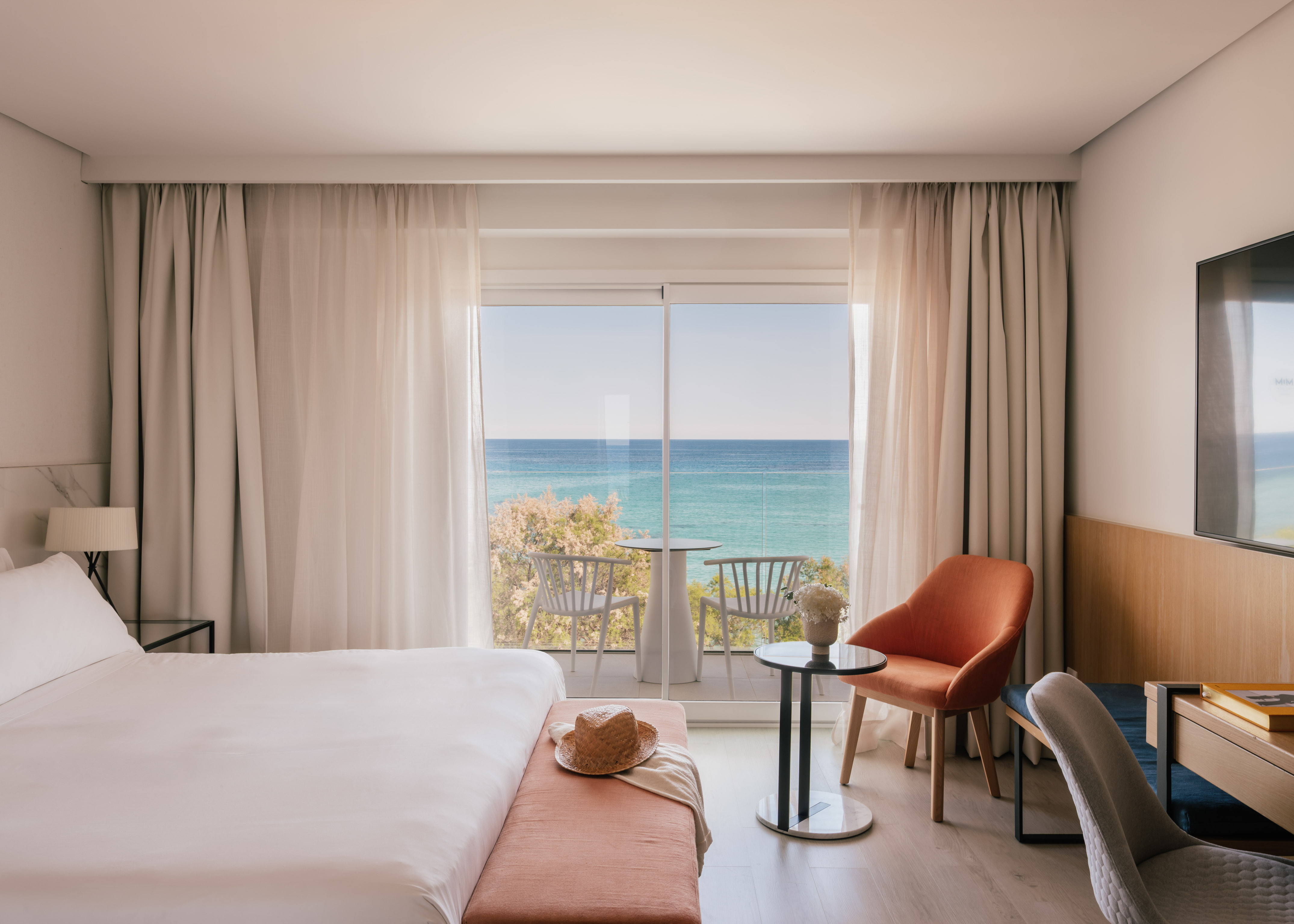 Habitación de hotel moderna con cama, balcón y vistas al mar.