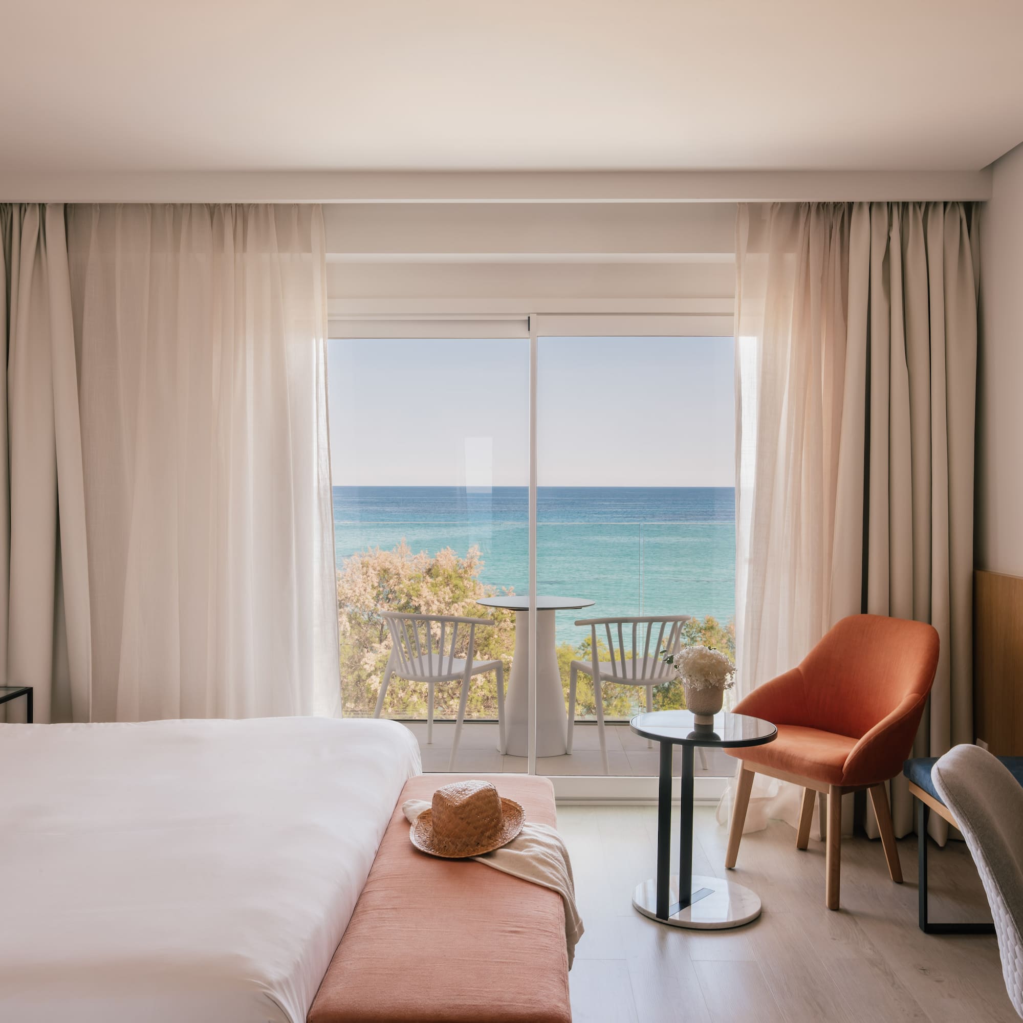 Hotel room with ocean view balcony, white bed, and modern design.