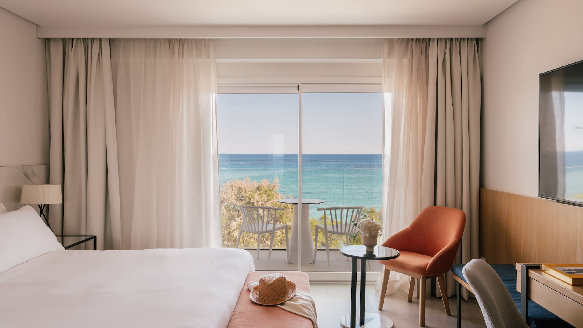 Hotel room with ocean view balcony, white bed, and modern design.