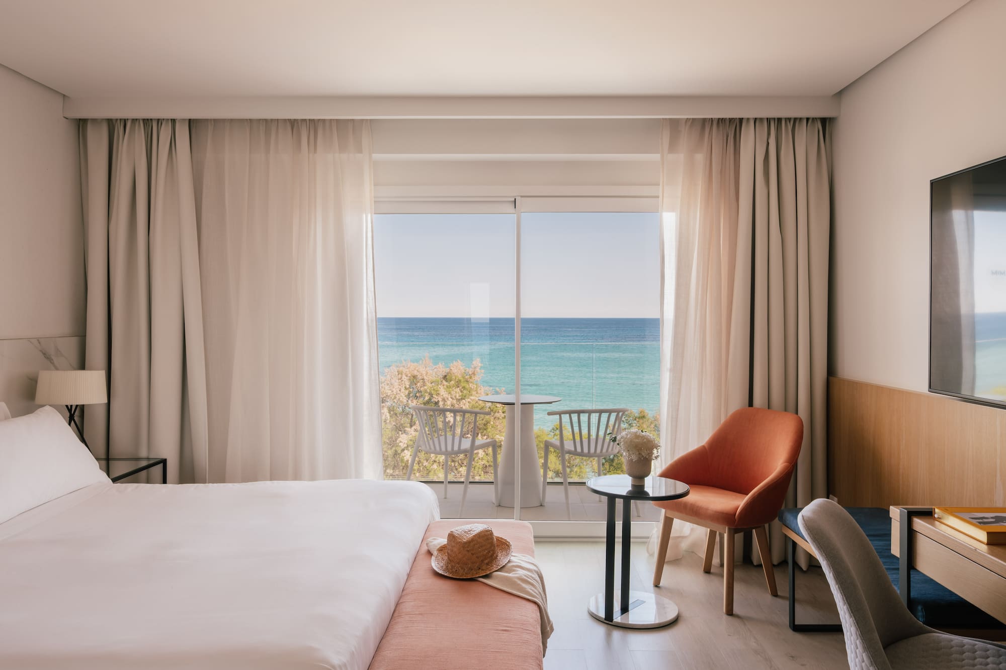 Habitación de hotel moderna con cama, balcón y vistas al mar.