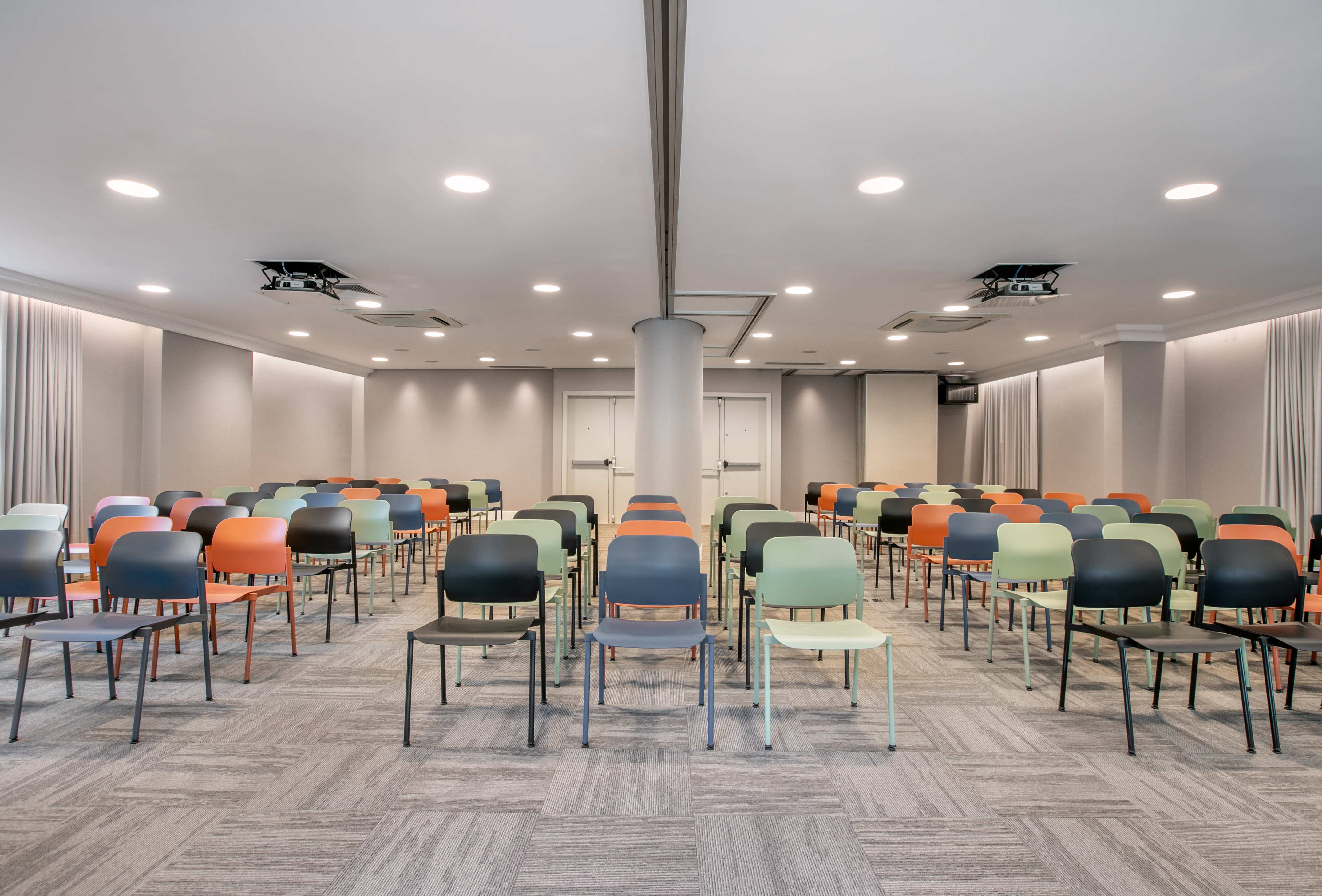 Modern conference room with rows of colorful chairs and projector.