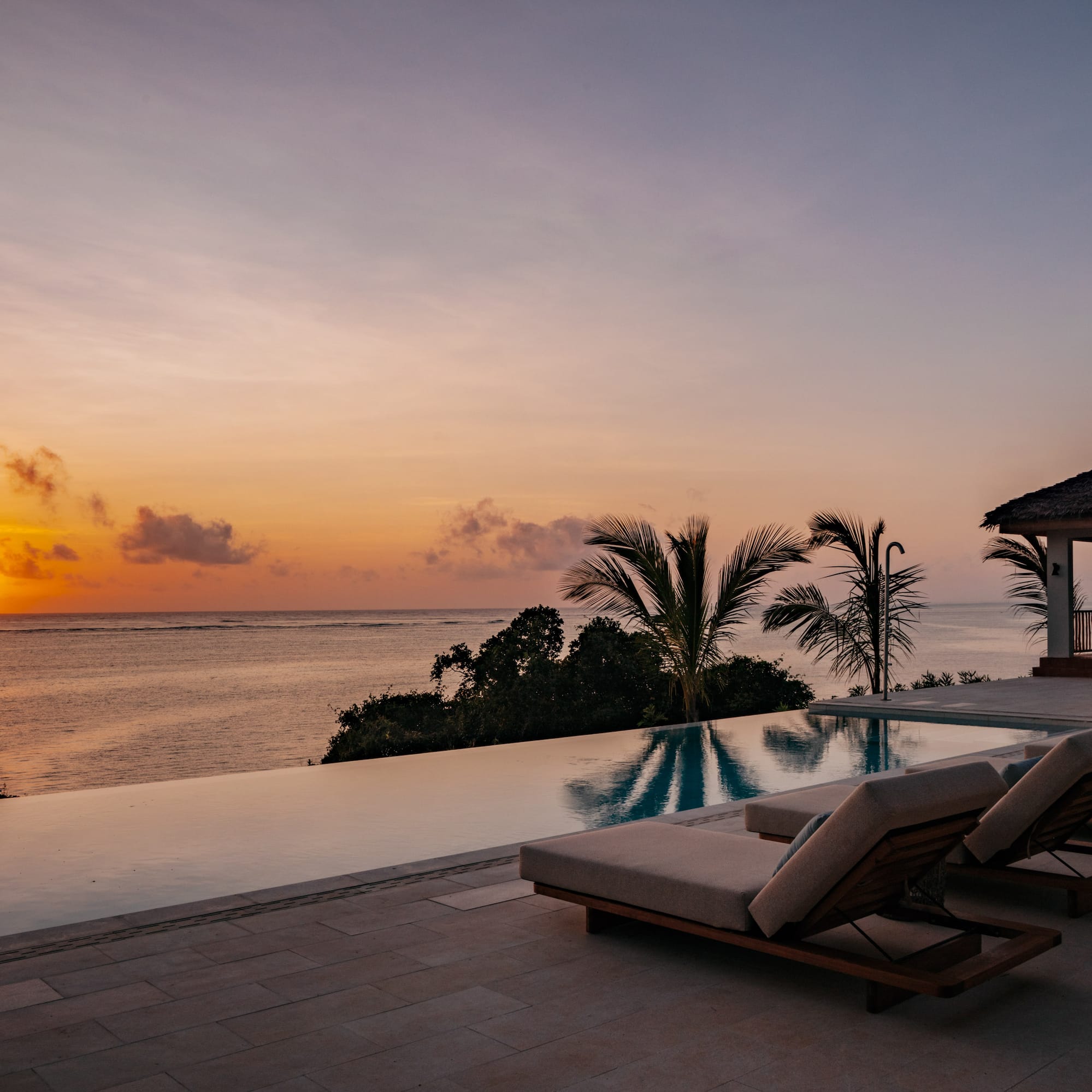 a pool with lounge chairs and a house overlooking the ocean