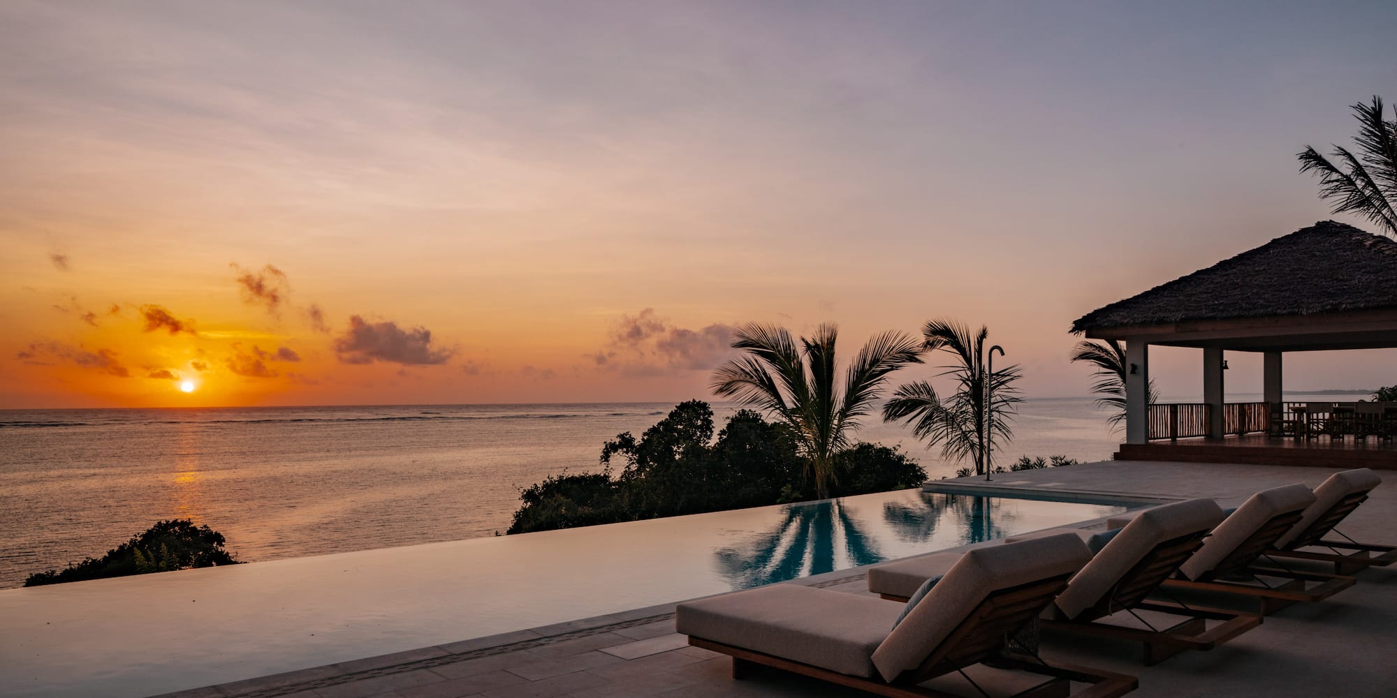 a pool with lounge chairs and a house overlooking the ocean