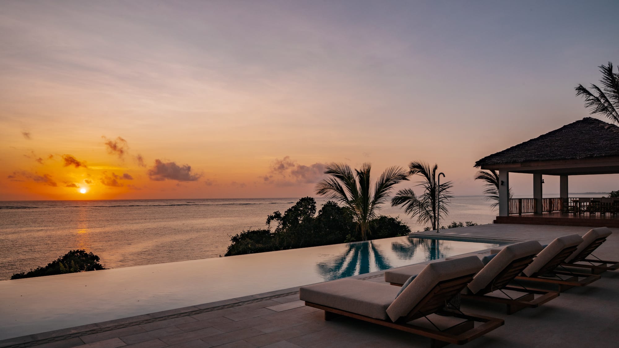 a pool with lounge chairs and a house overlooking the ocean
