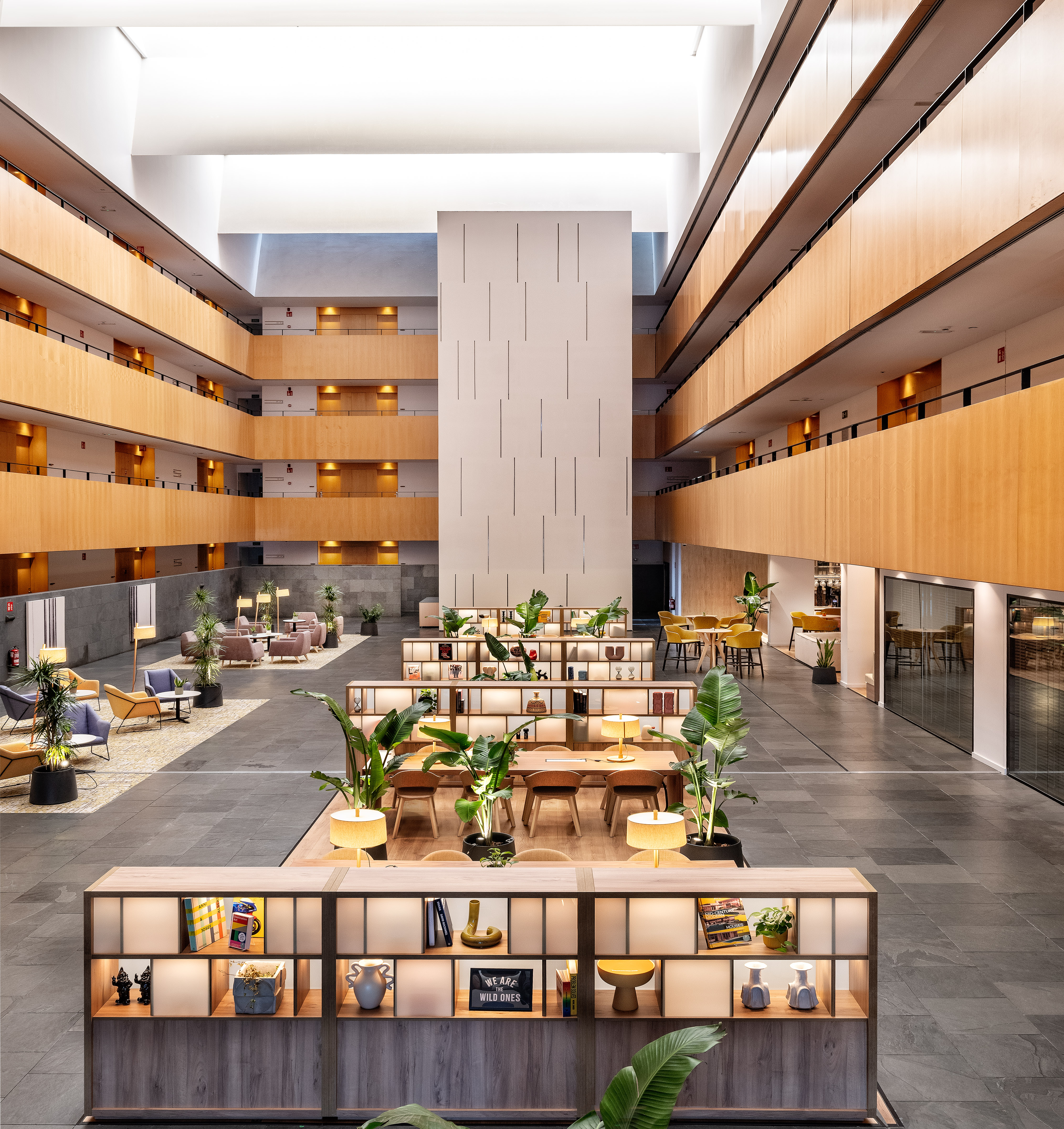 Modern hotel atrium with wood levels, lounge seating, and interior plants.