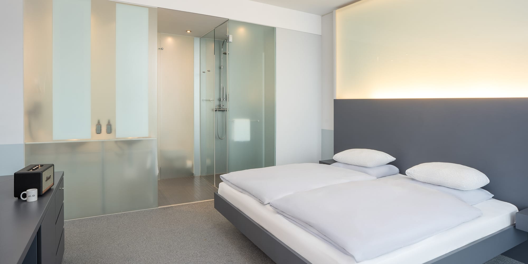 a bedroom with a glass shower and a bed
