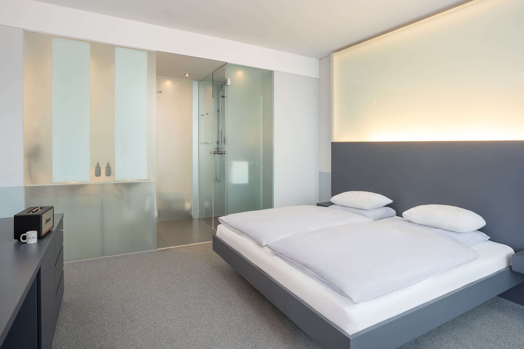 a bedroom with a glass shower and a bed