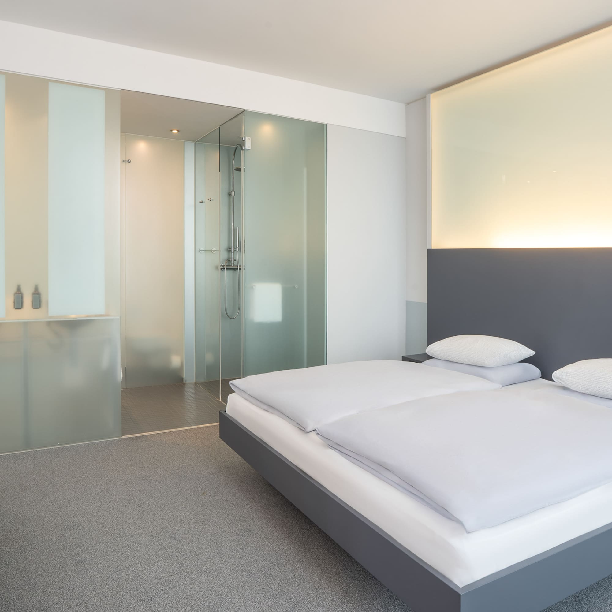 a bedroom with a glass shower and a bed
