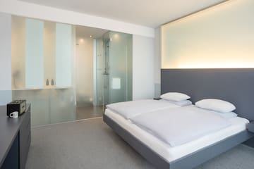 a bedroom with a glass shower and a bed
