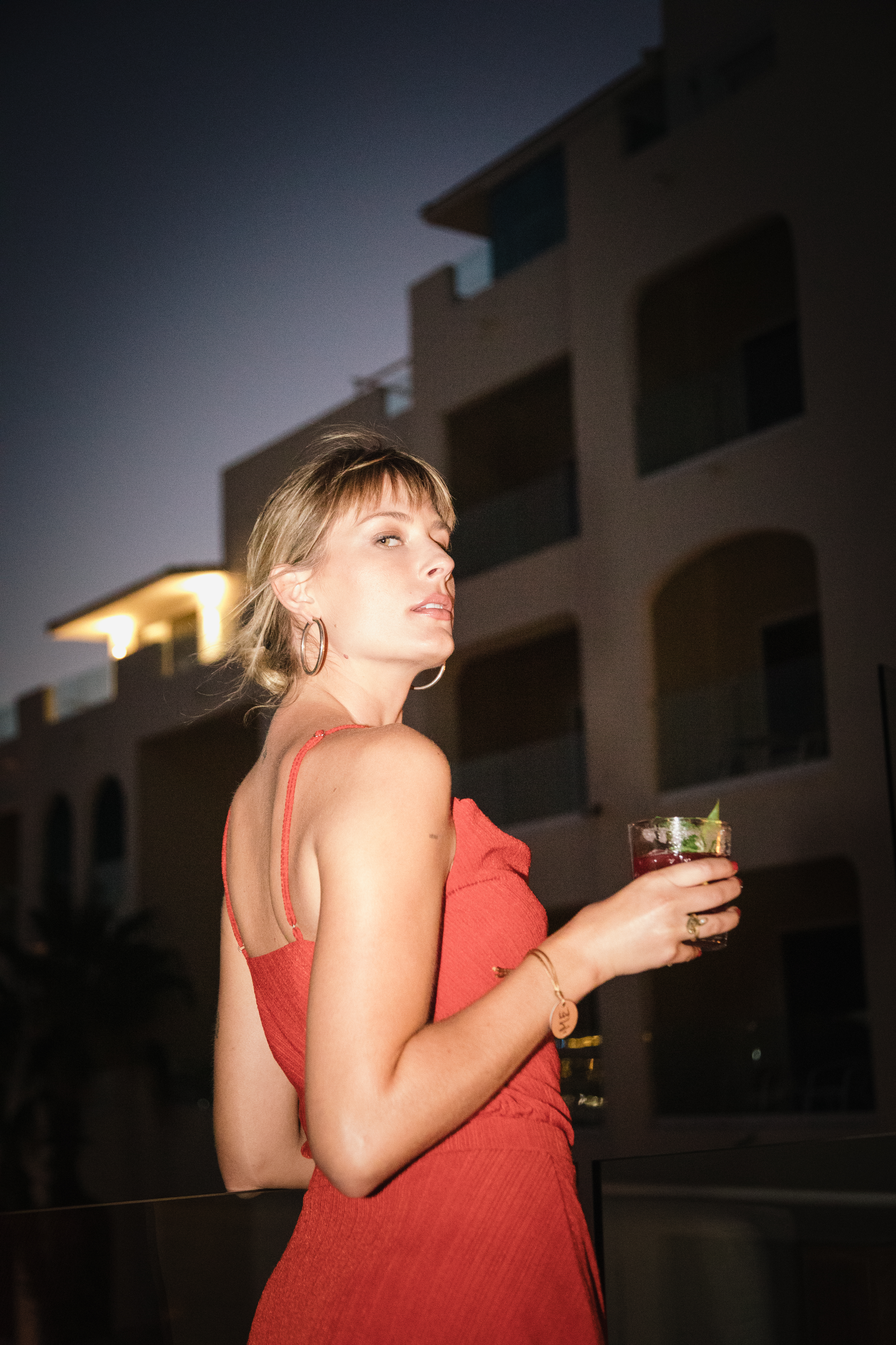 a woman in a red dress holding a drink