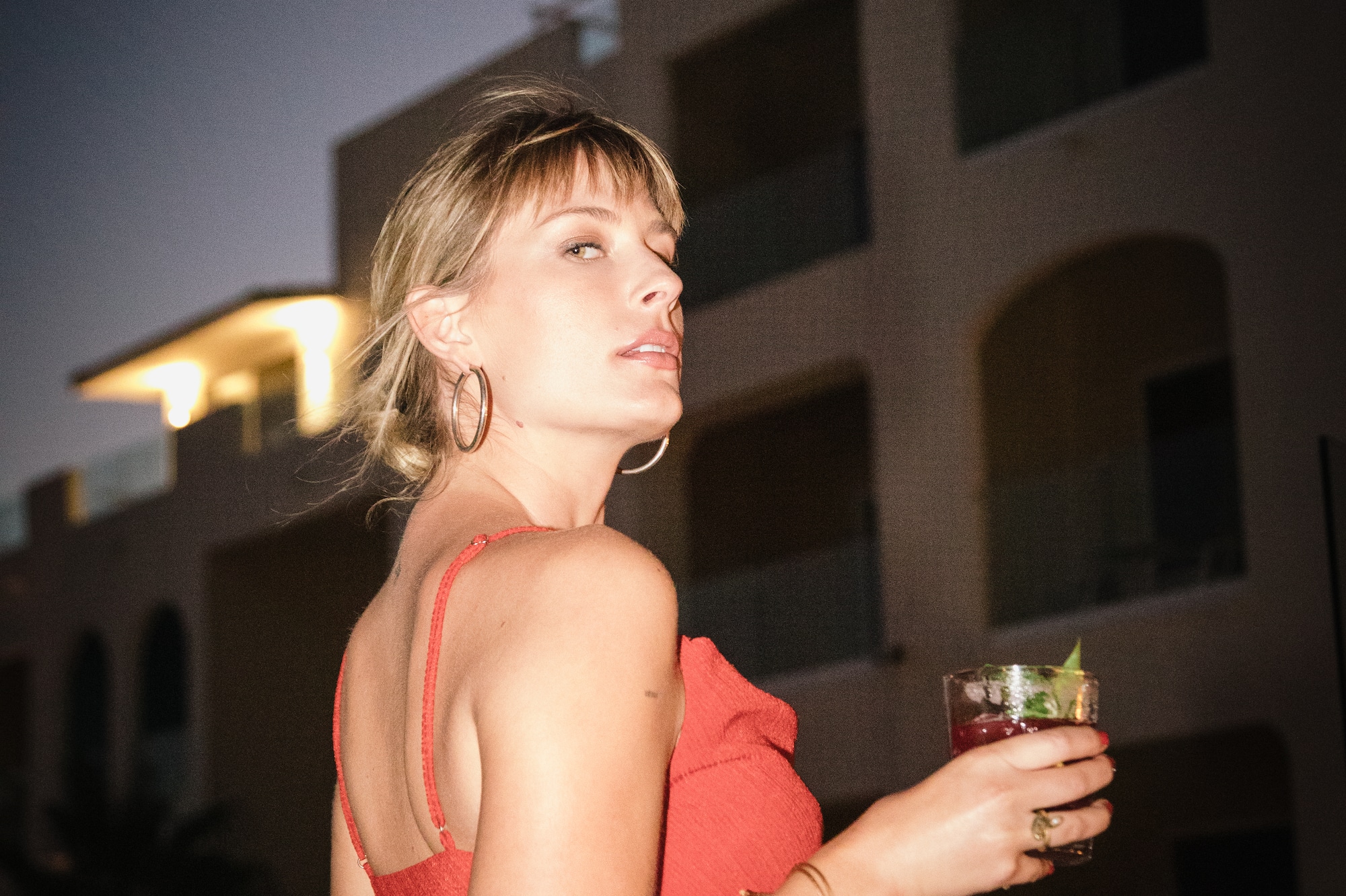 a woman in a red dress holding a drink