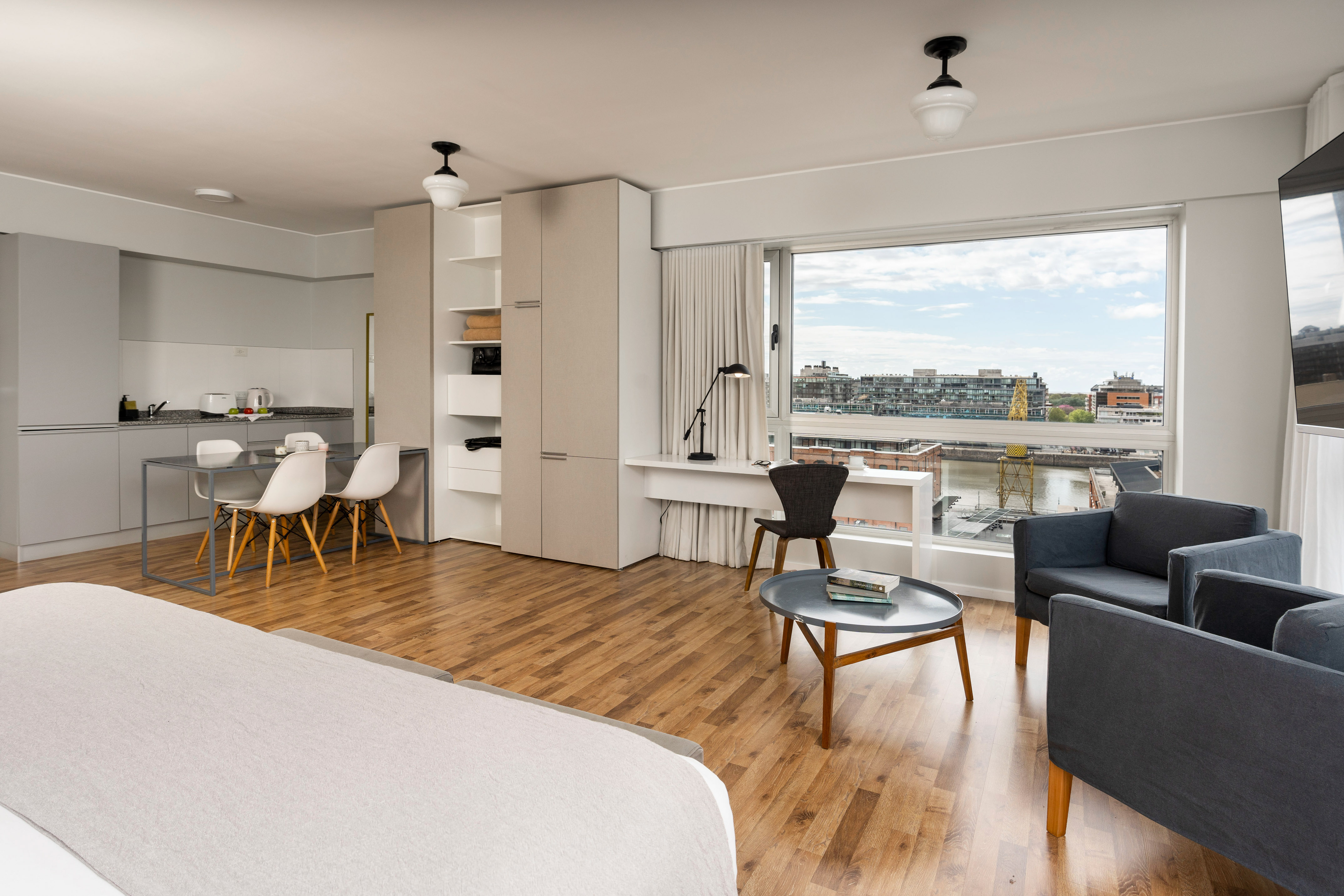 Modern studio apartment with waterfront city view, living, dining, and kitchen areas.