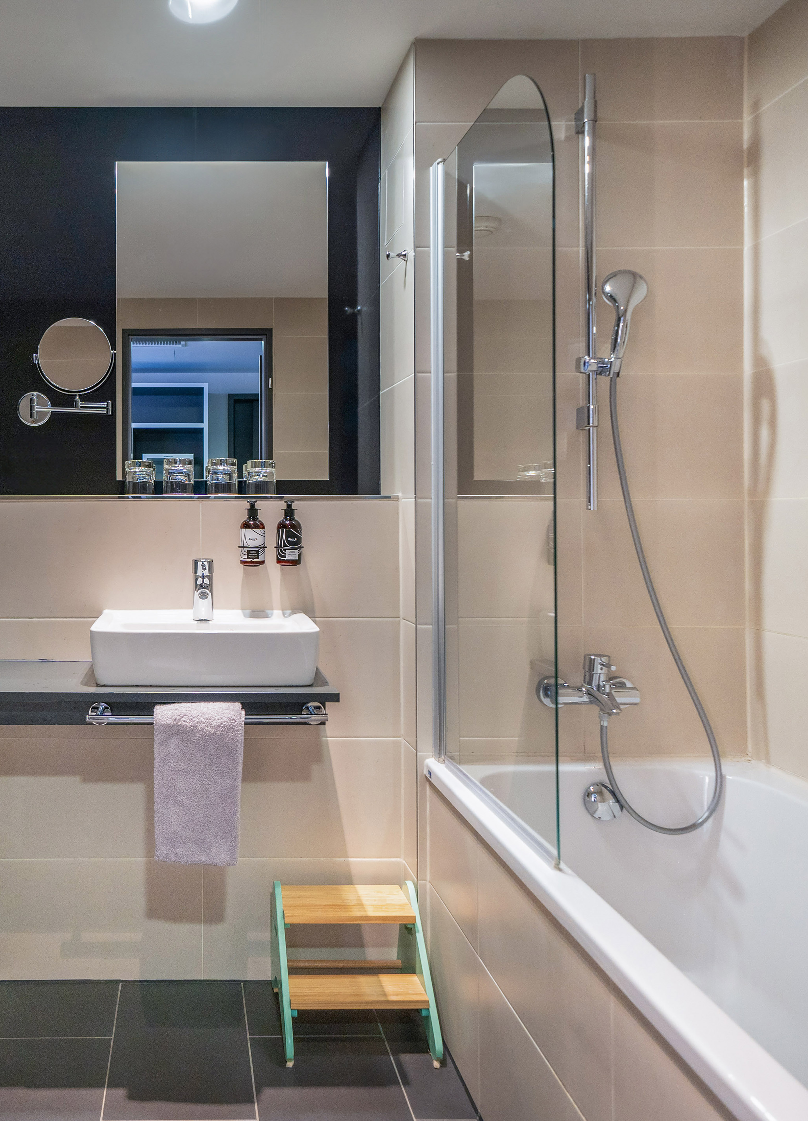Modern beige bathroom: rectangular sink, large mirror, bathtub, glass shower.