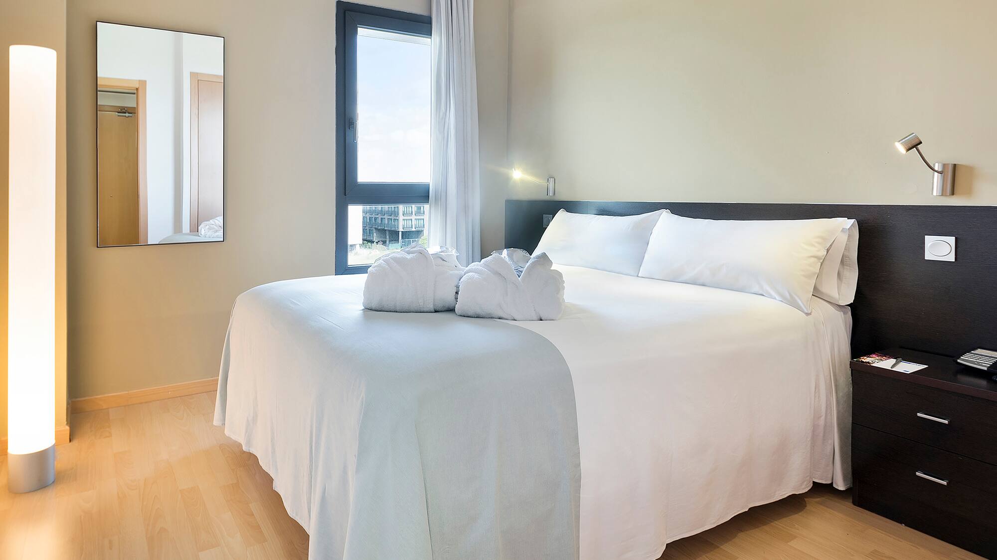 a bed with white sheets and towels