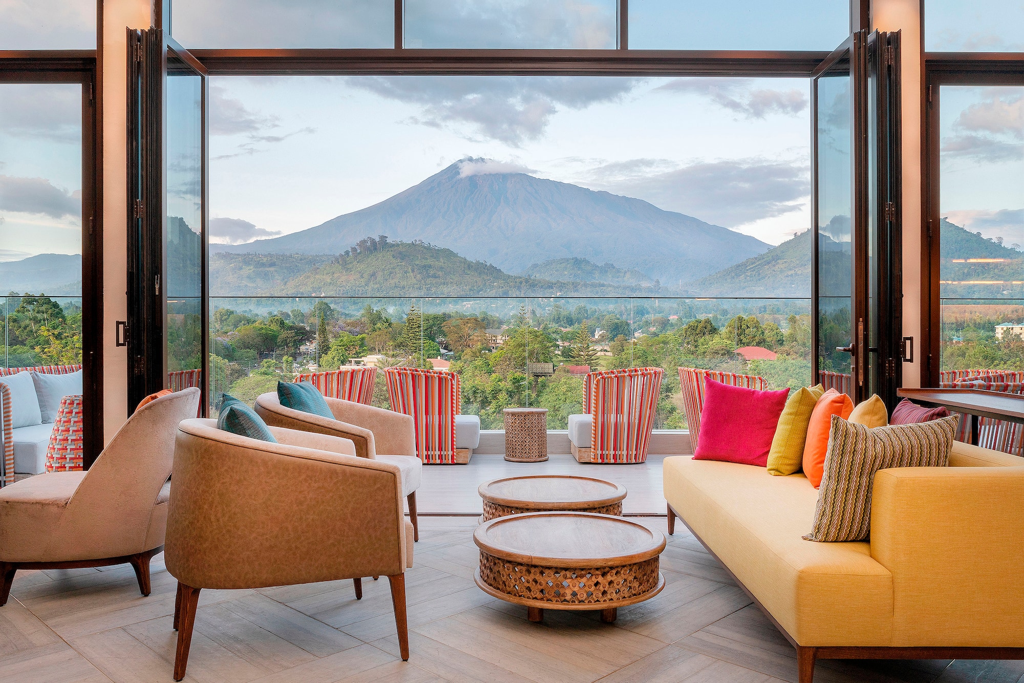 Luxury balcony lounge with vibrant seating and stunning volcanic mountain view.