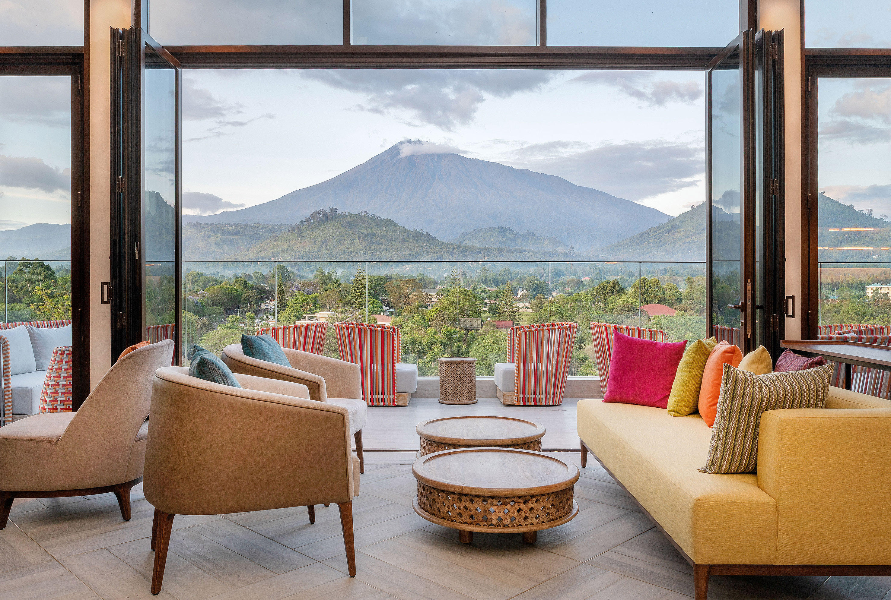 Luxury balcony lounge with vibrant seating and stunning volcanic mountain view.