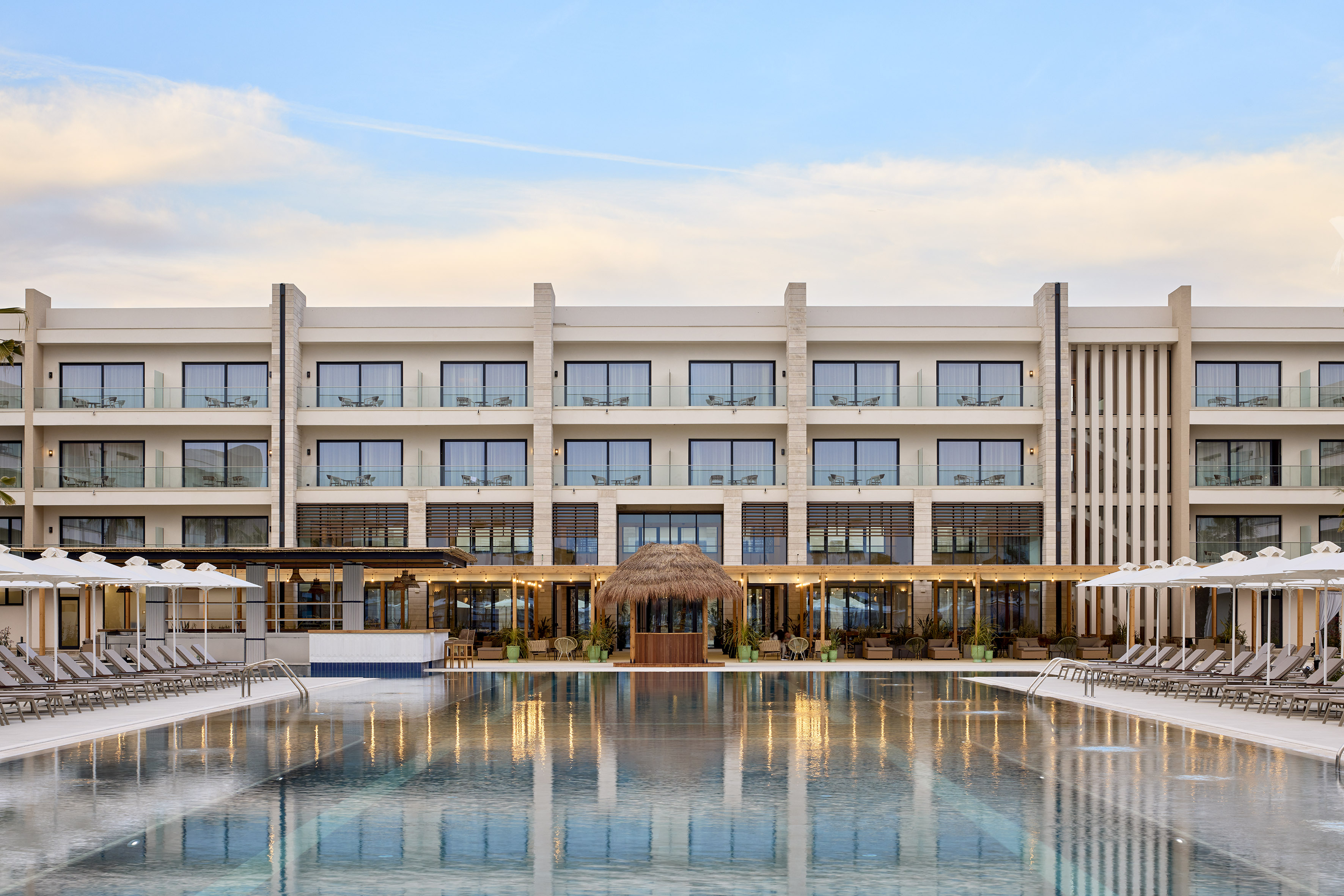 Luxury resort hotel with large reflecting pool, balconies, and poolside bar.