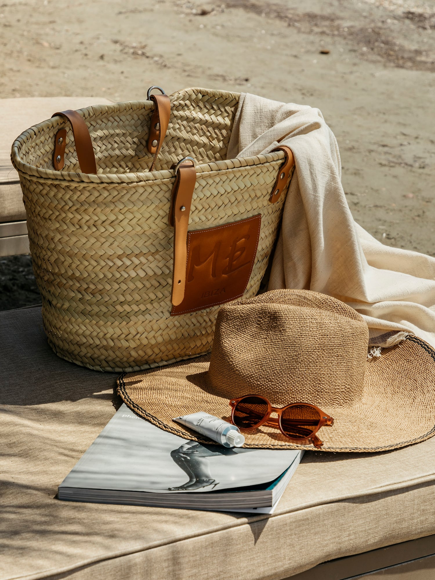 a straw hat and sunglasses next to a bag and a book