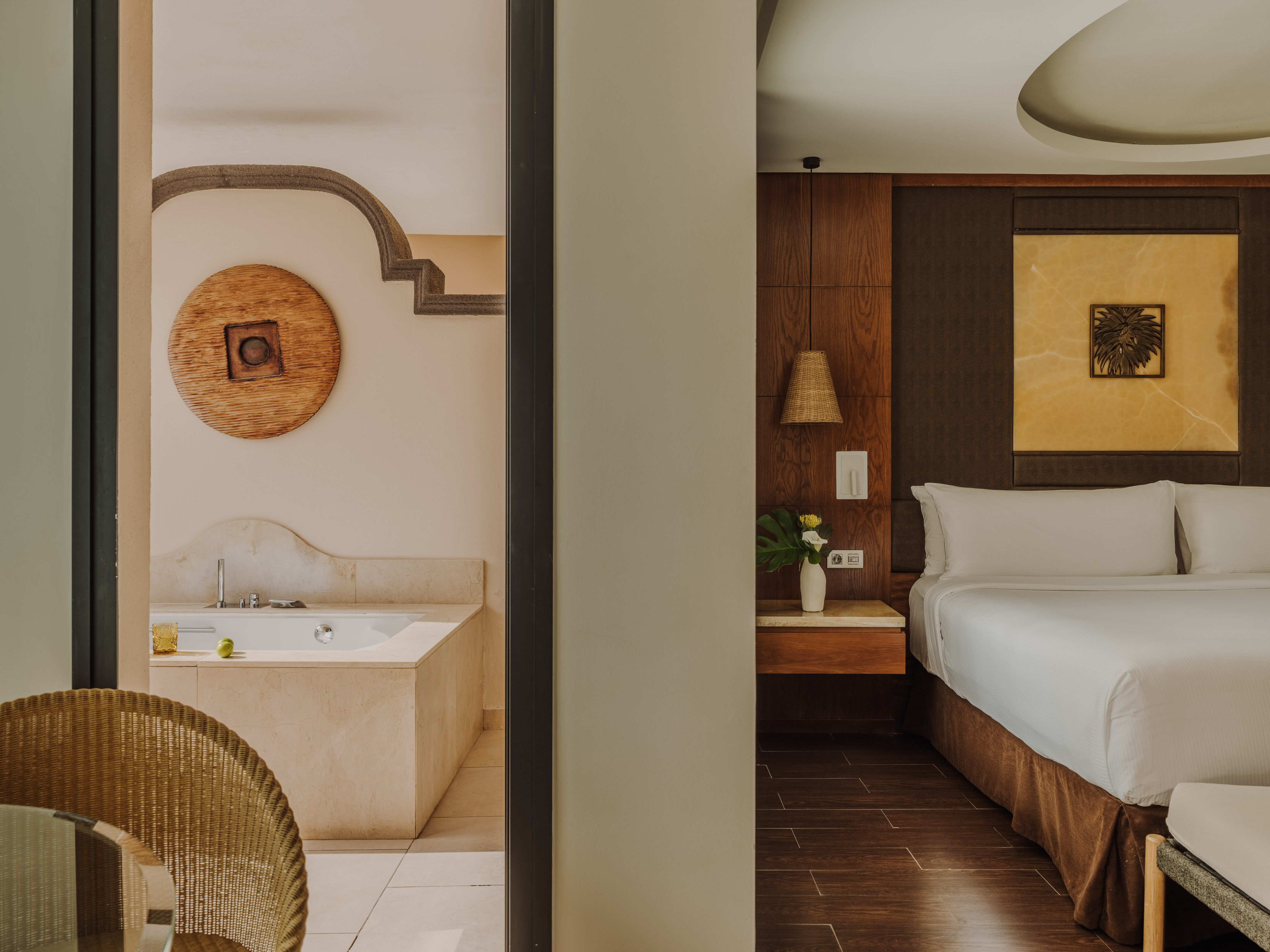 Luxurious hotel suite with modern bedroom and spacious bathroom with large tub.