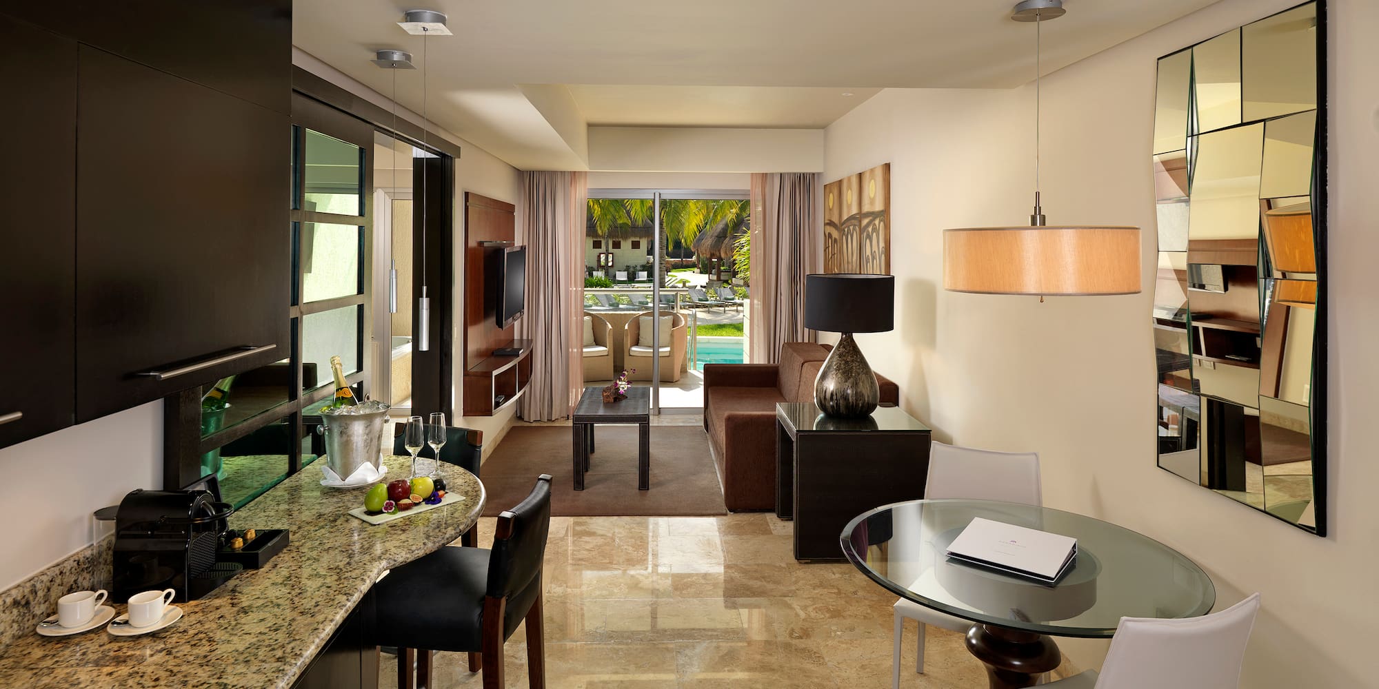 Modern luxury suite: living room, kitchen bar, tropical pool view.