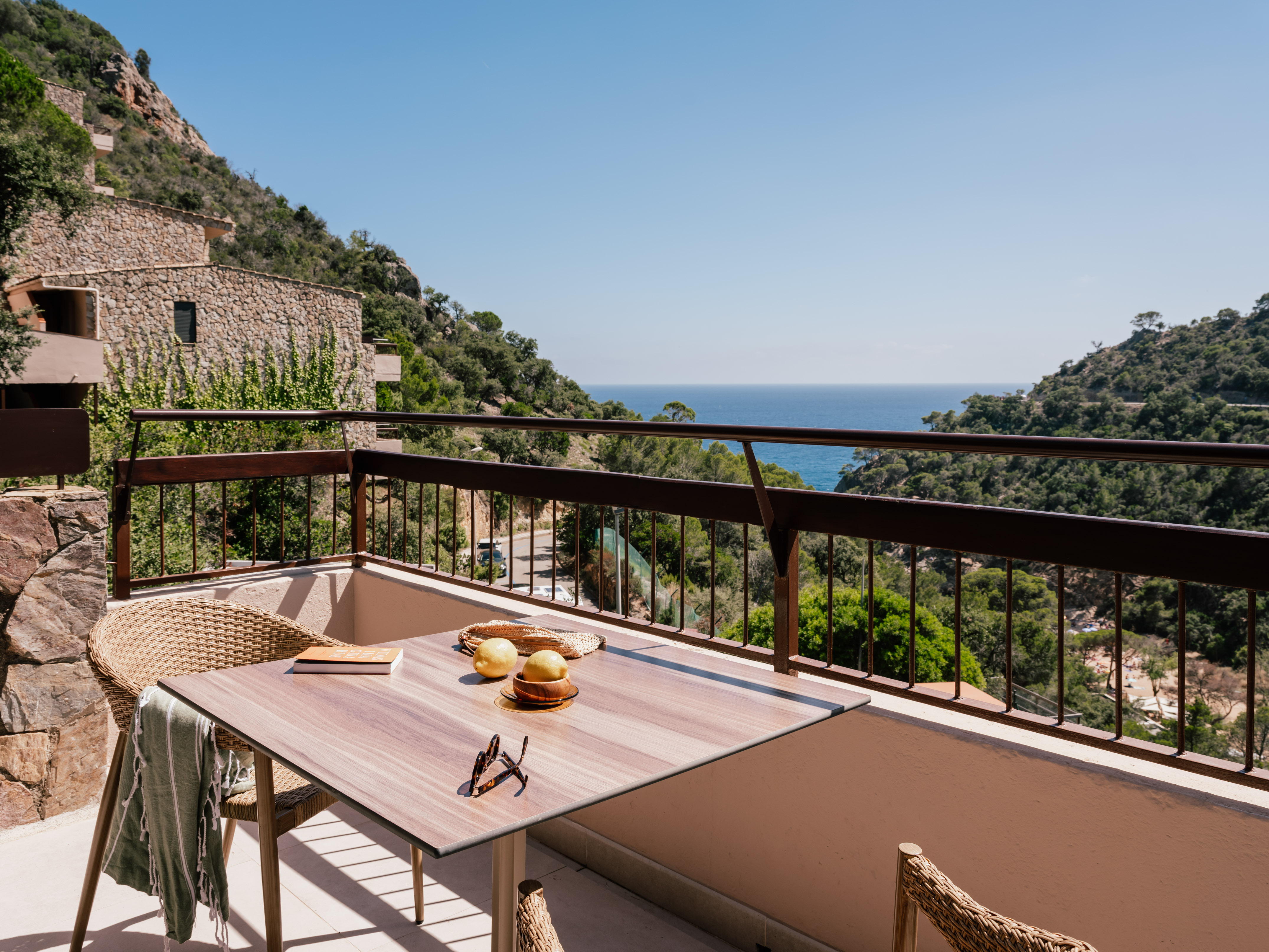 Mediterranean coastal resort balcony with table, lemons, and sea view.