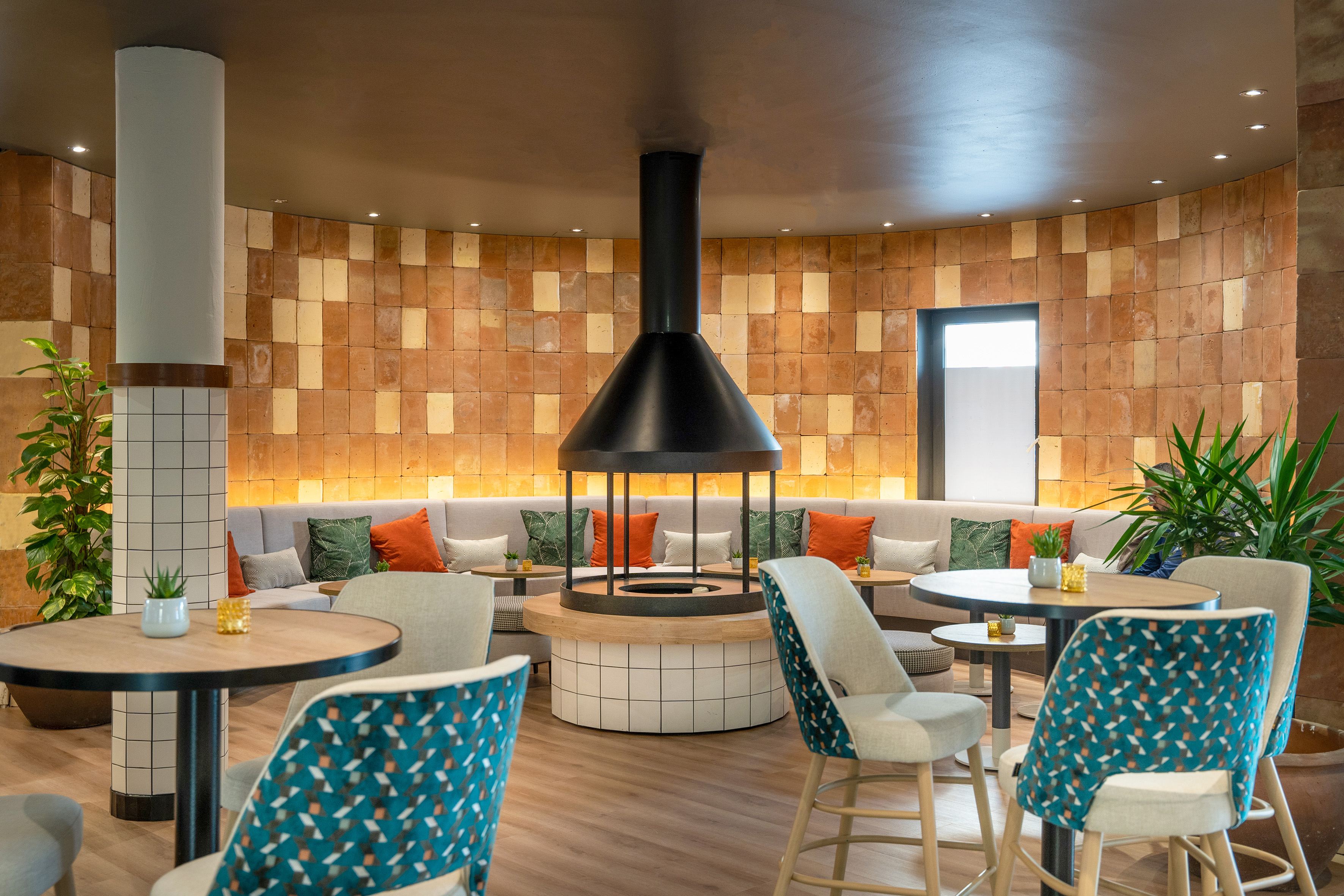 Modern hotel lounge with circular fireplace, curved brick wall, and contemporary seating.