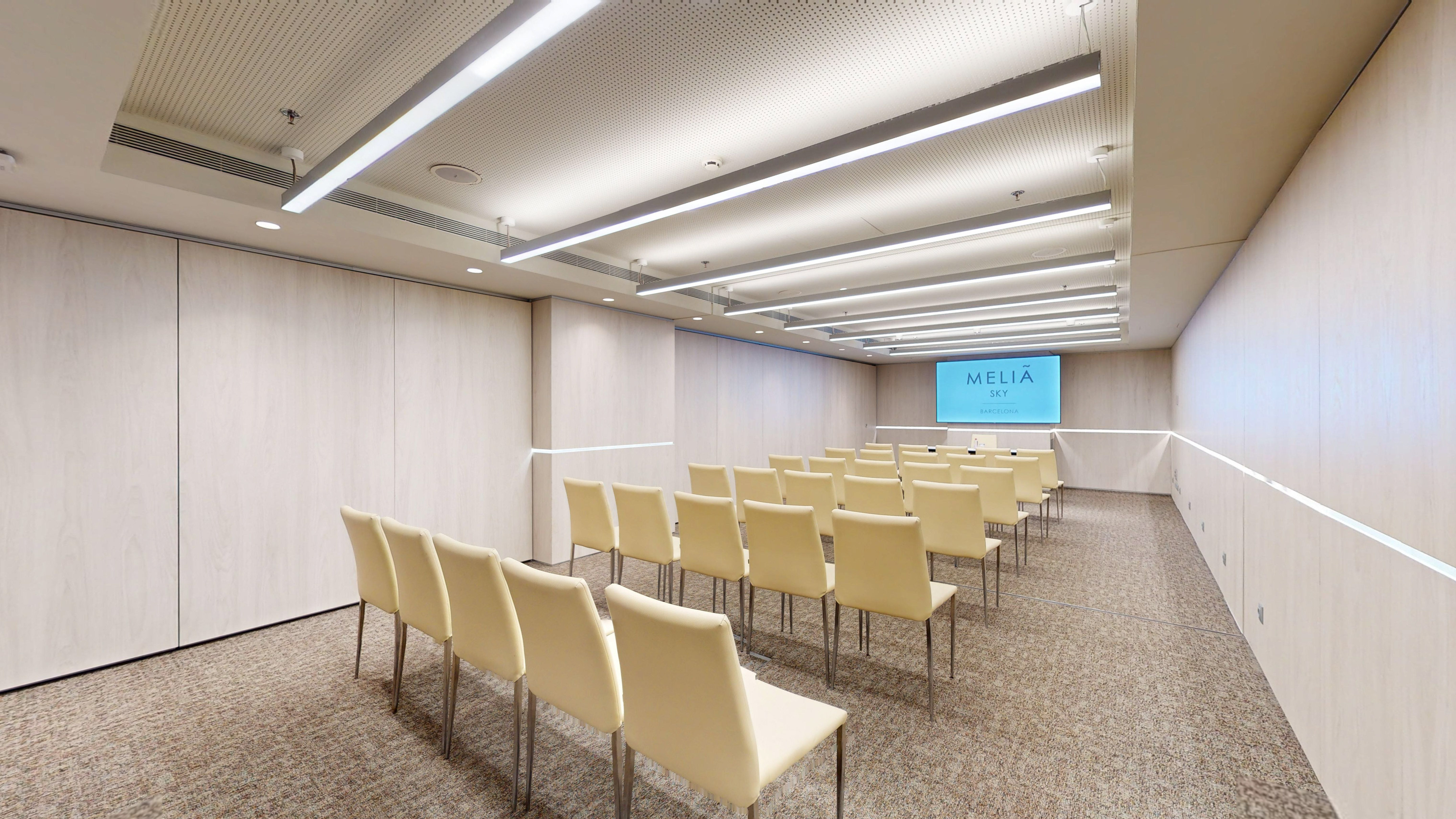 Melia Sky Barcelona meeting room with rows of chairs and screen.