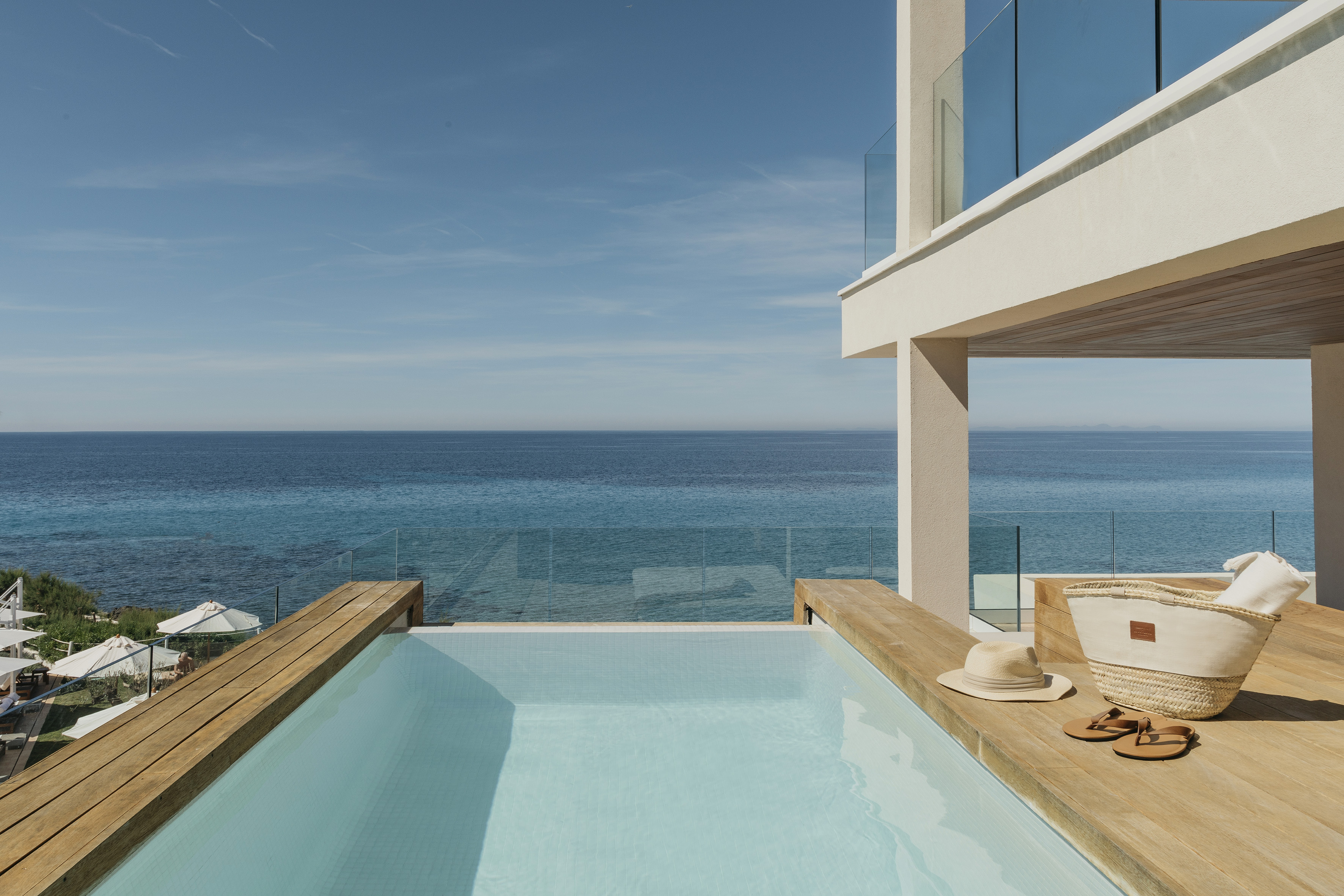 Luxury private pool with ocean view, wooden deck, and modern building.