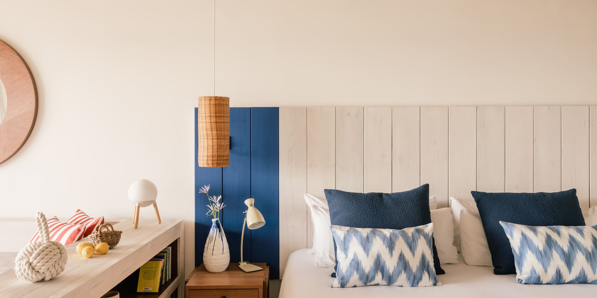 Dormitorio estilo costero con cama, cojines azules y cabecero de madera.