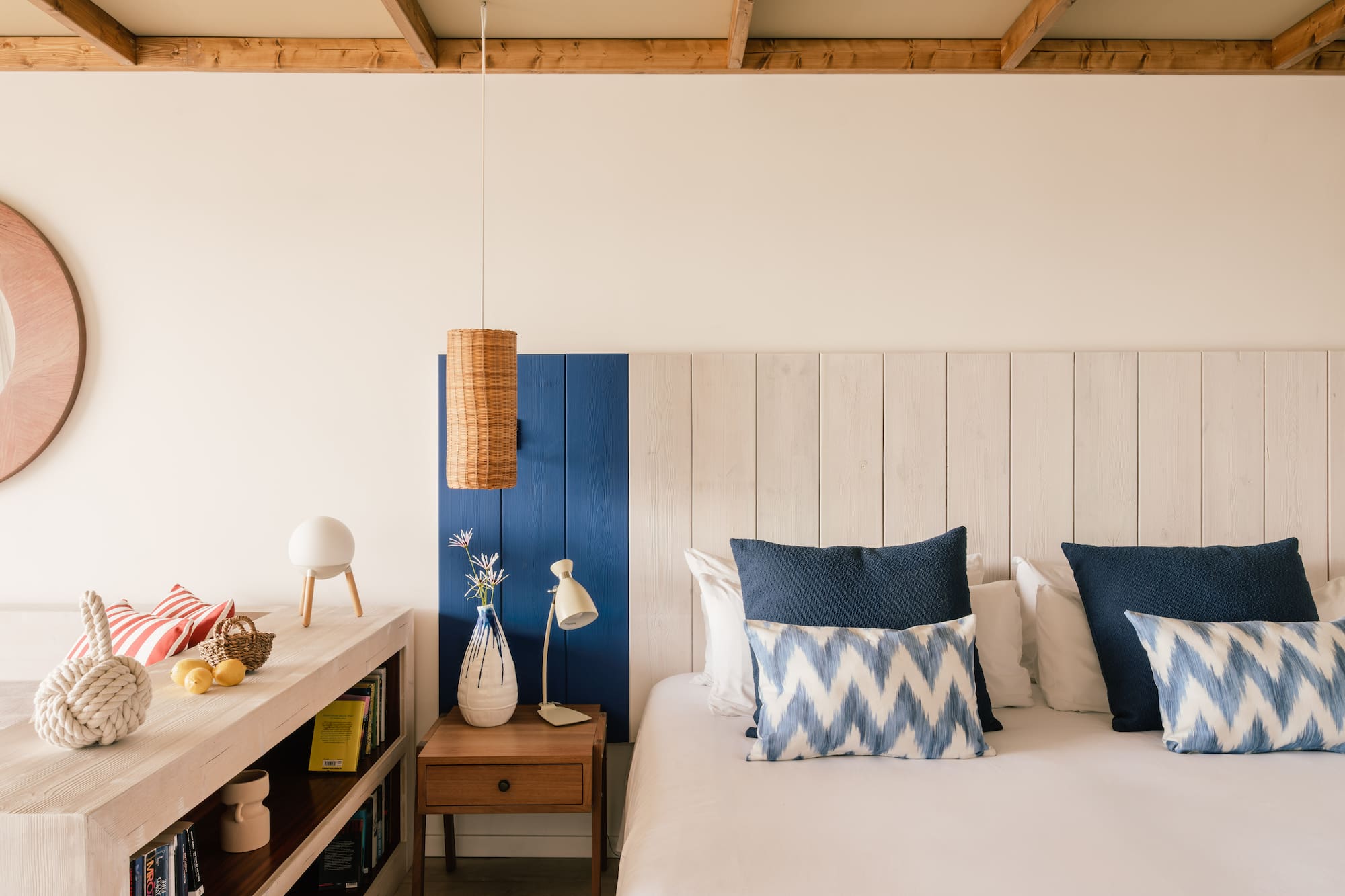 Dormitorio estilo costero con cama, cojines azules y cabecero de madera.