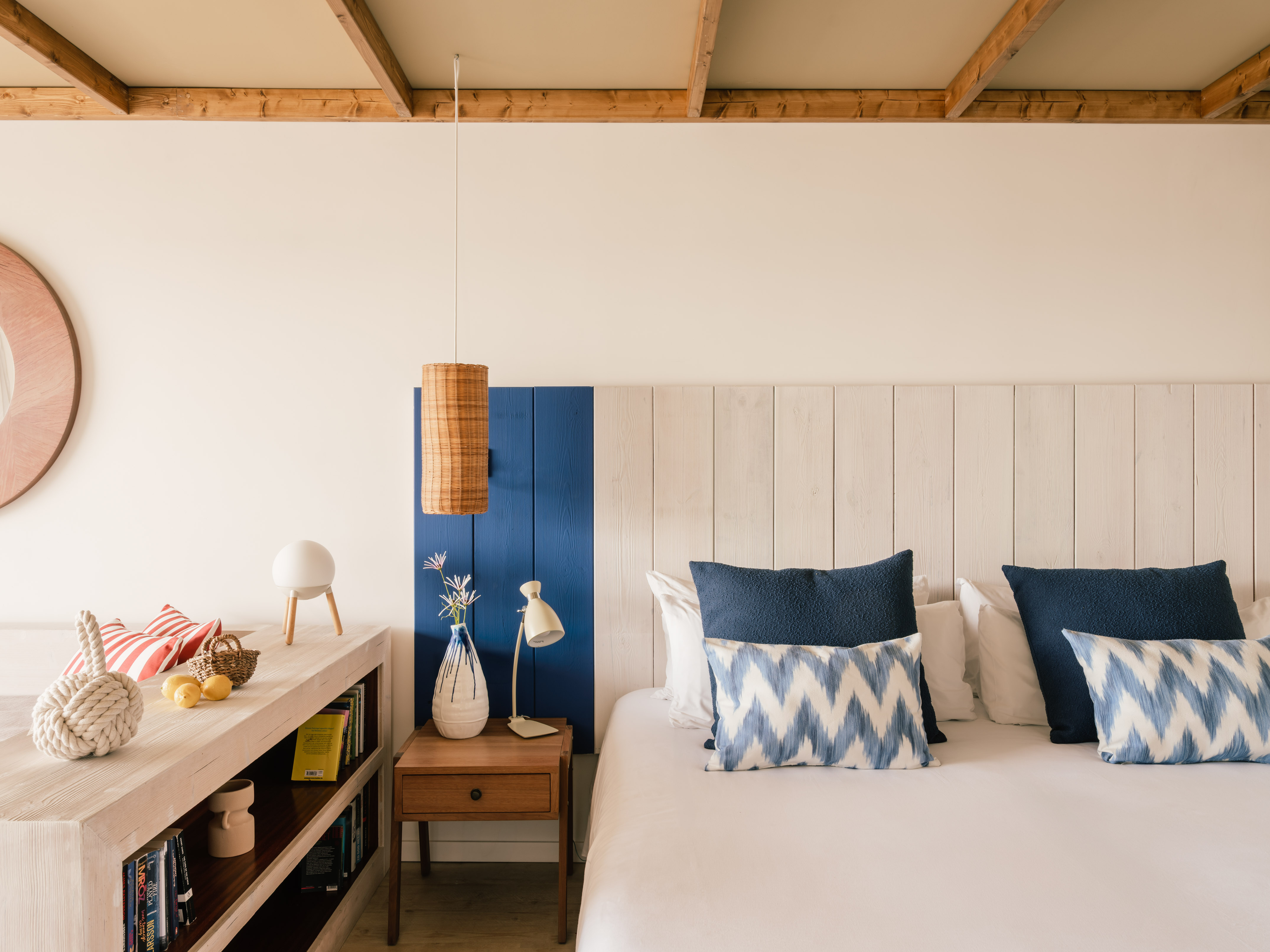 Dormitorio estilo costero con cama, cojines azules y cabecero de madera.