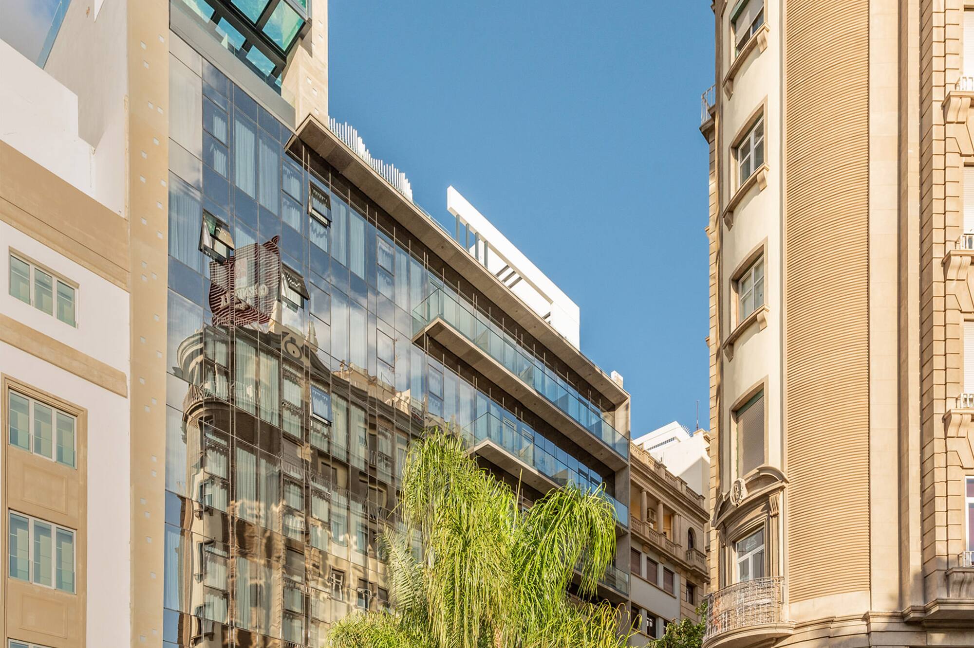 INNSiDE hotel: modern glass building, rooftop pool, palm trees, city street.